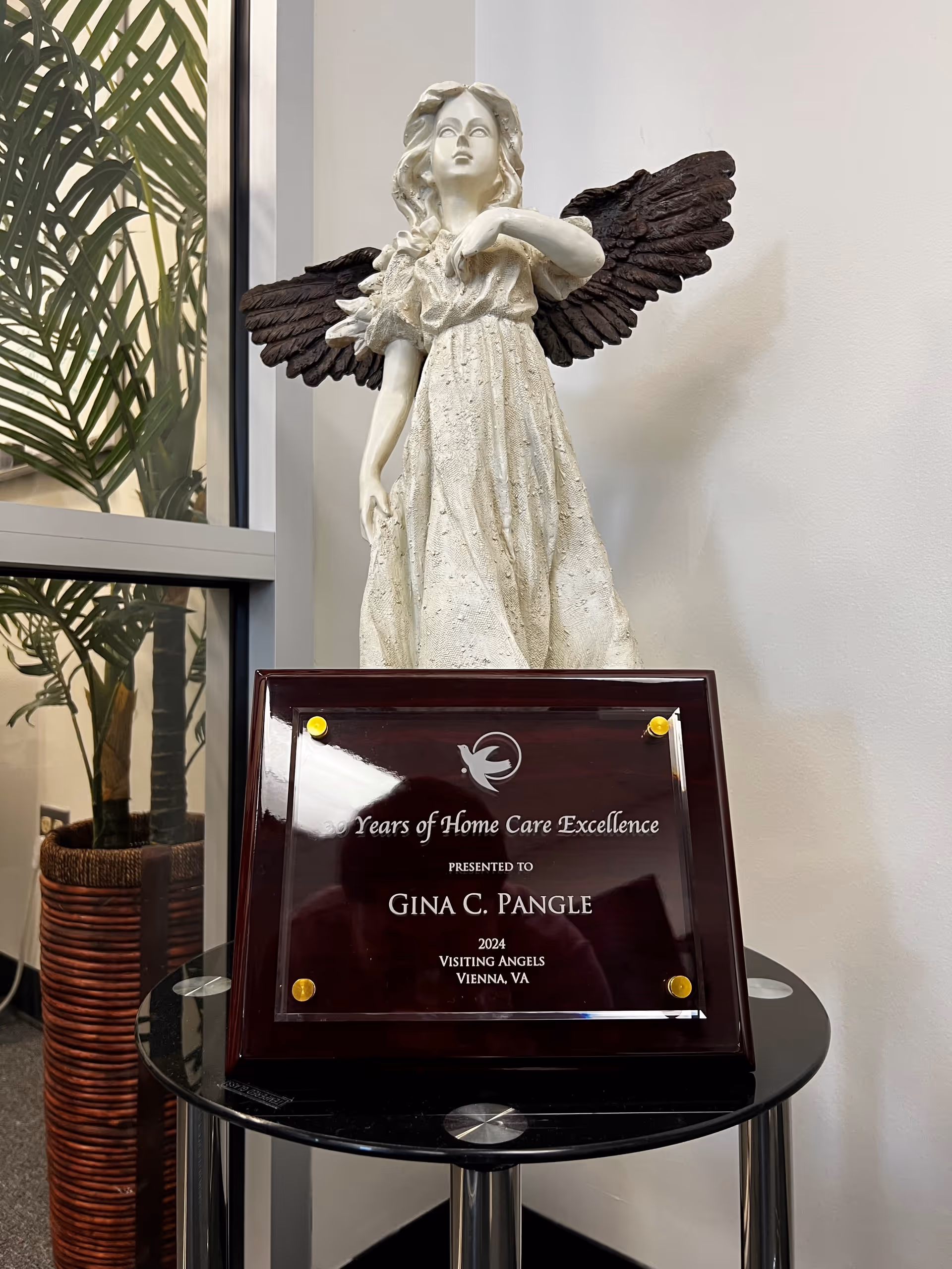 Angelic statue with wings and a plaque on a round glass table in a lobby