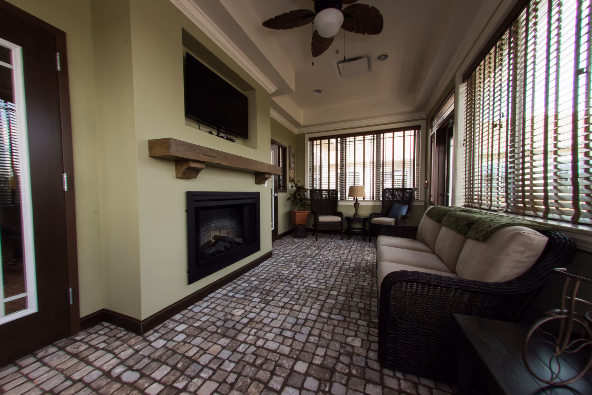 Indoor living room lounge featuring a fireplace, TV, and large windows with blinds.