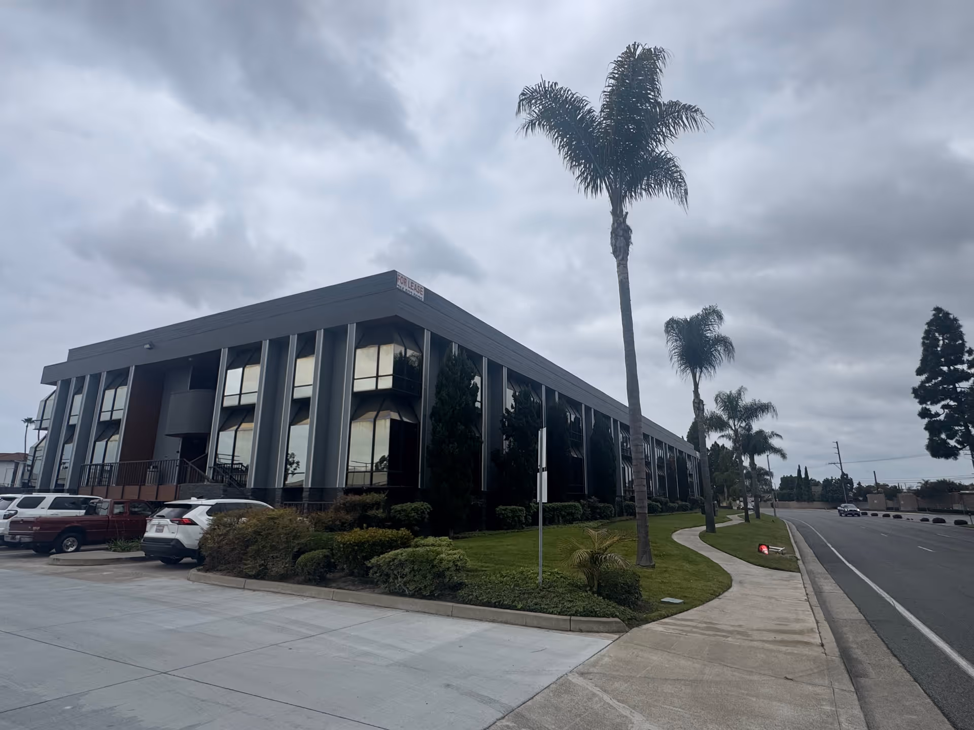 Exterior view of a modern two-story building with large windows and palm trees.