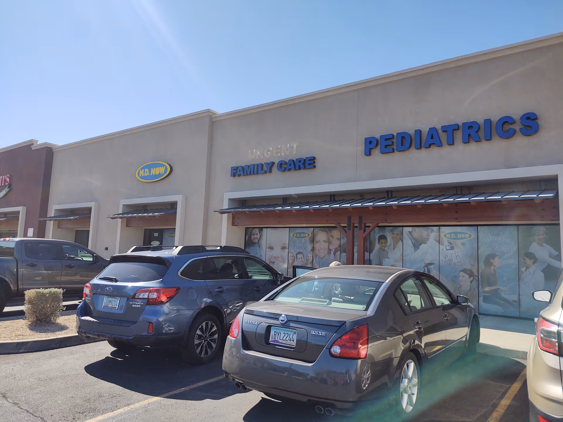 Exterior view of a medical clinic strip with MD Now urgent care and pediatrics.