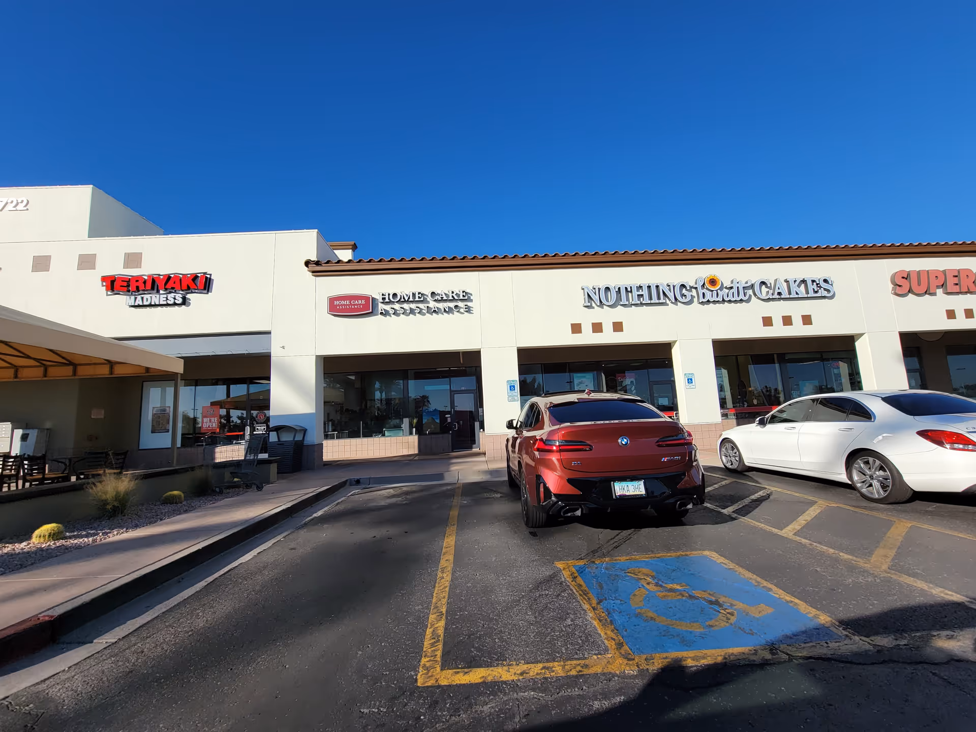 Exterior view of a shopping plaza with parked cars and storefronts.