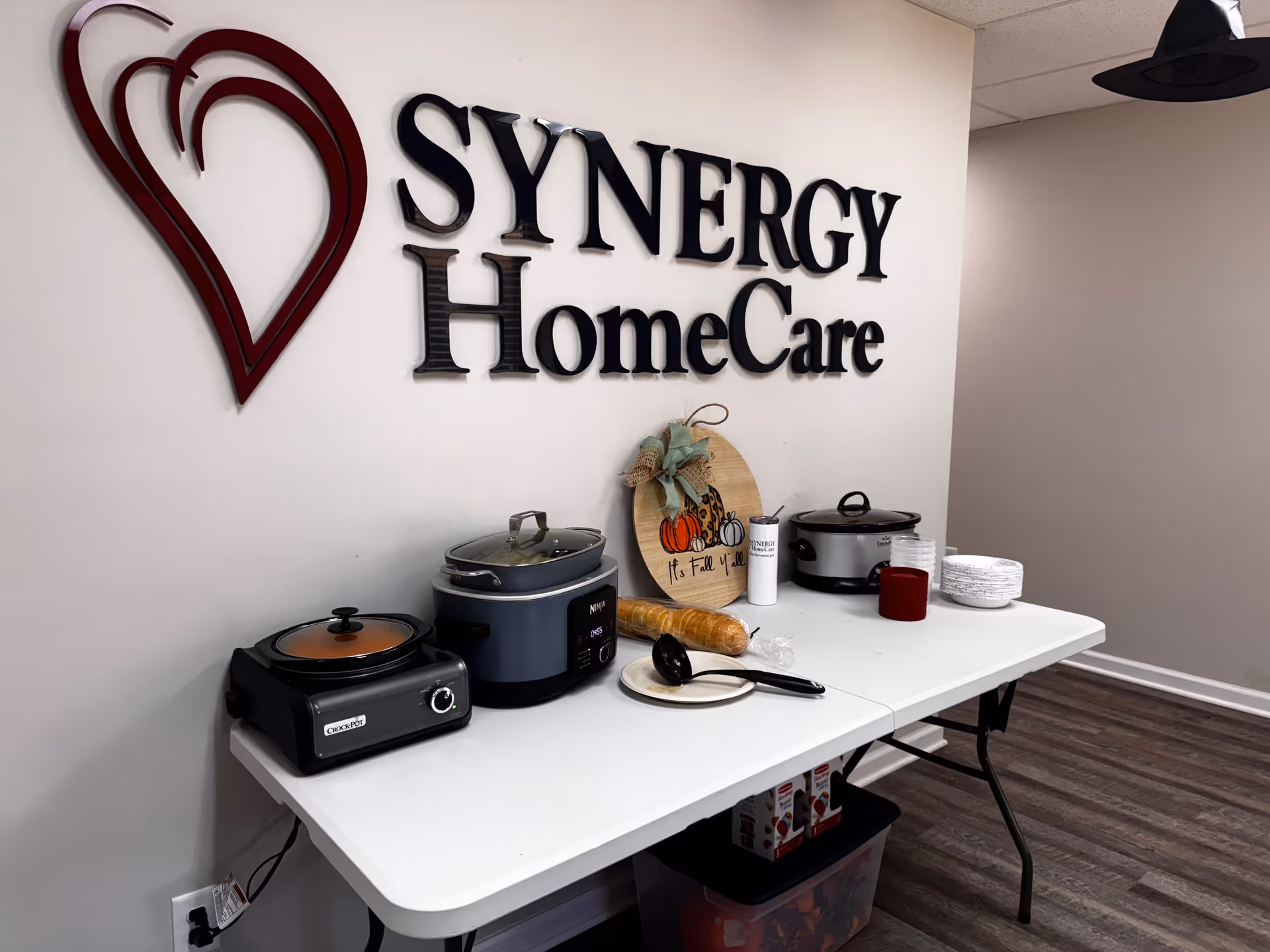 Interior showing SYNERGY HomeCare sign and a table with kitchen appliances.