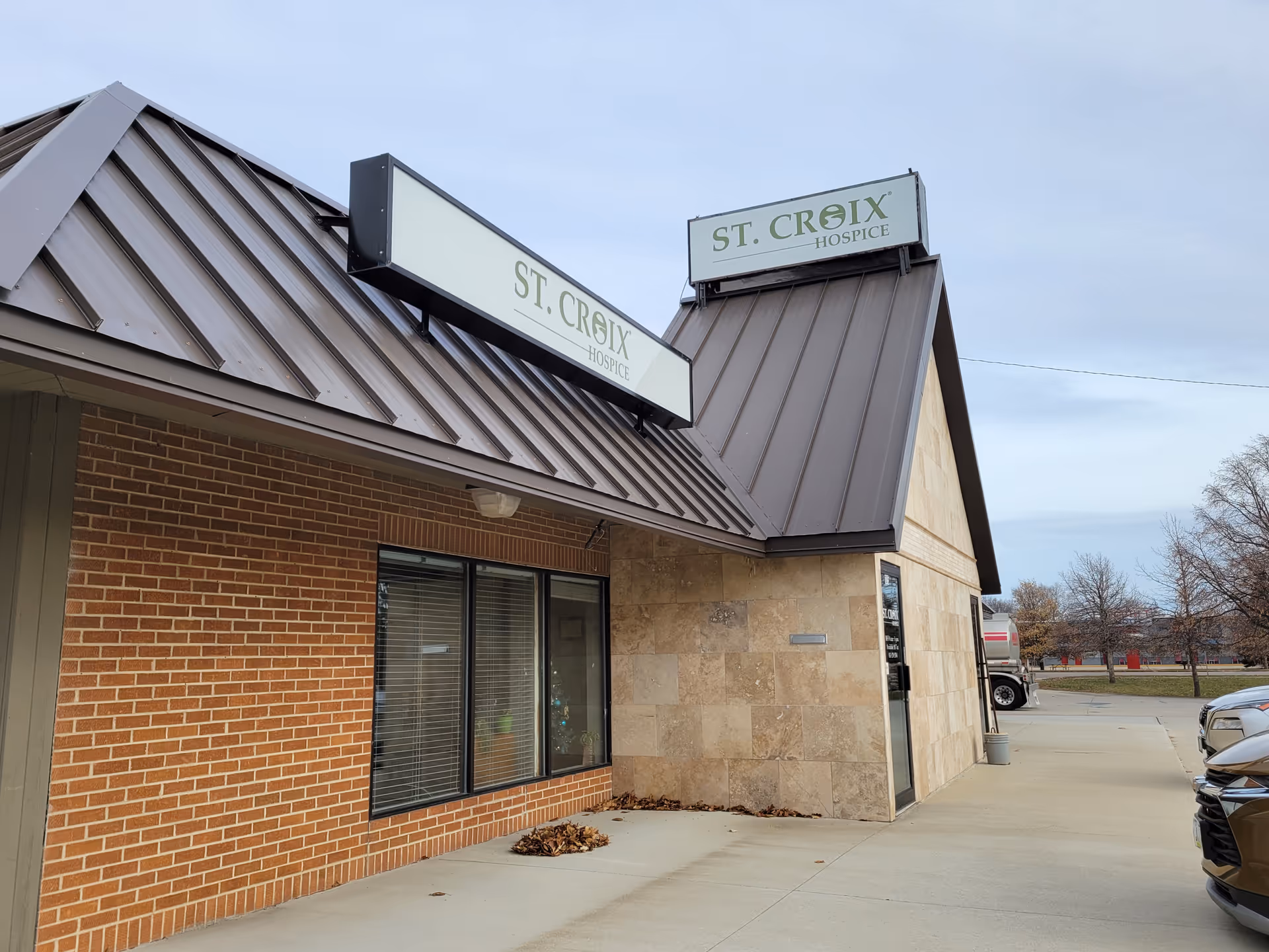 Exterior view of a St. Croix Hospice building with brick, stone facade and signs.