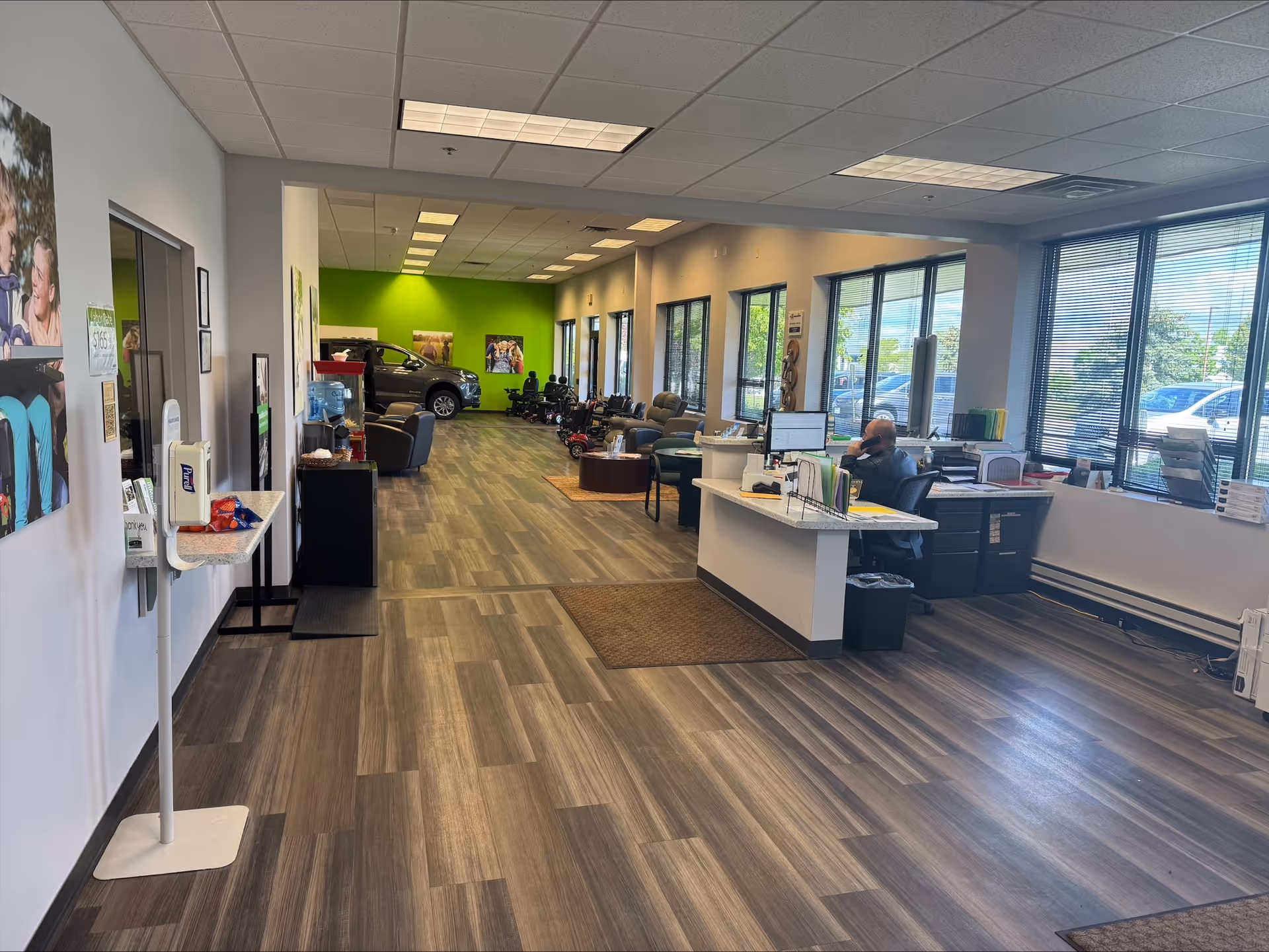 Bright lobby area with a reception desk, seating, computers, and large windows.