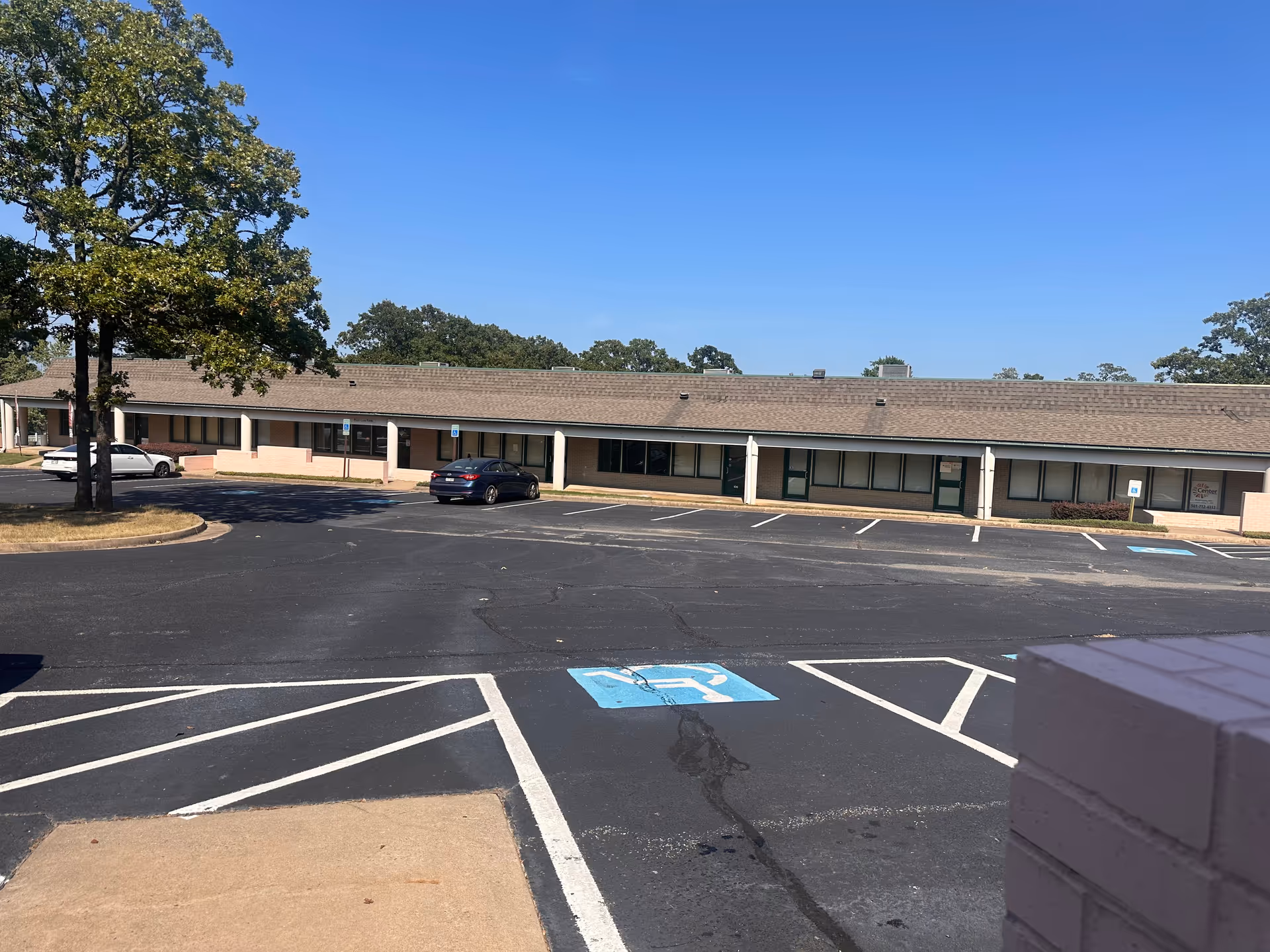 Single-story senior living facility exterior with a parking lot and blue sky.