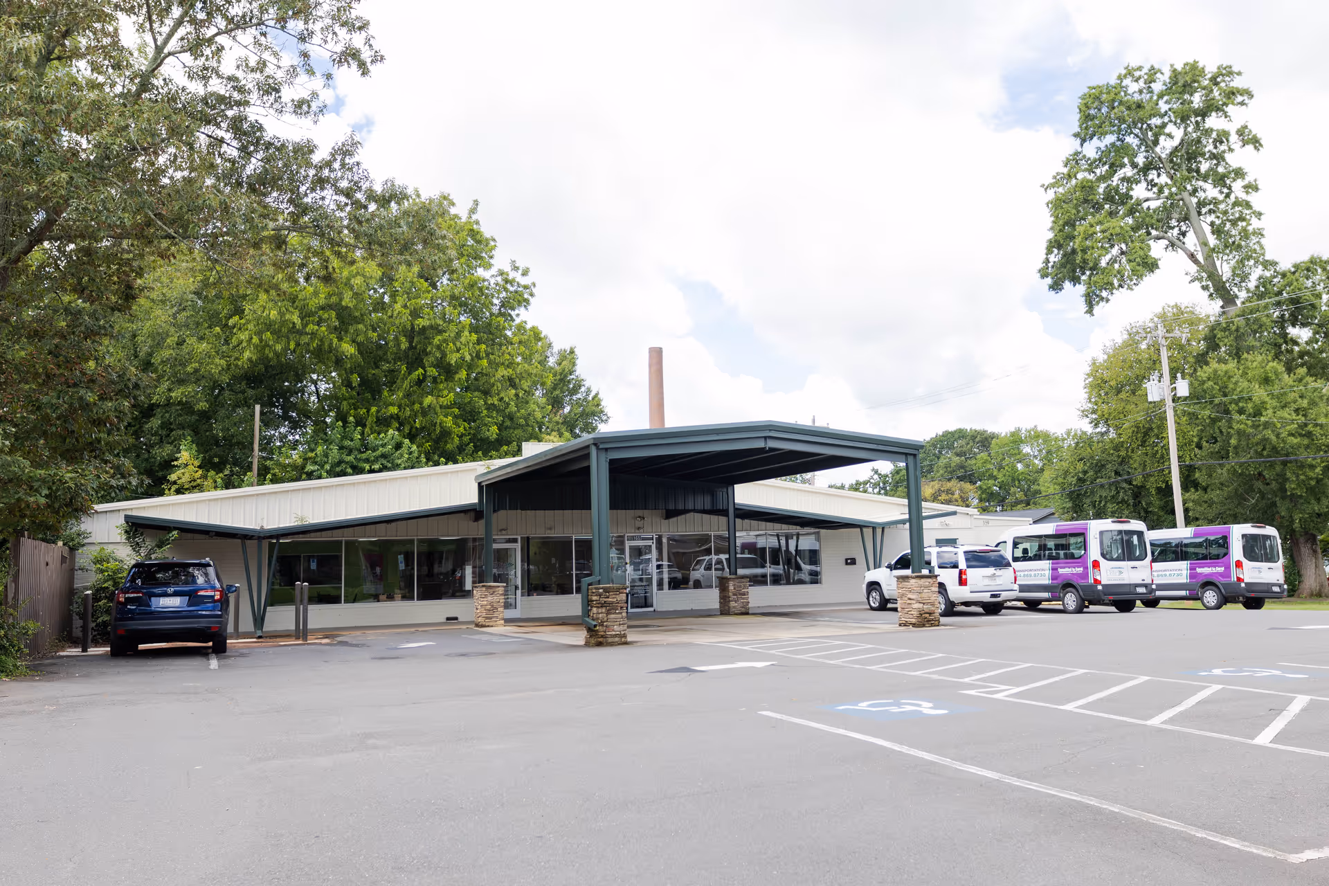 Exterior view of Elite Home Care and Day Centers with a covered entrance and parked buses.