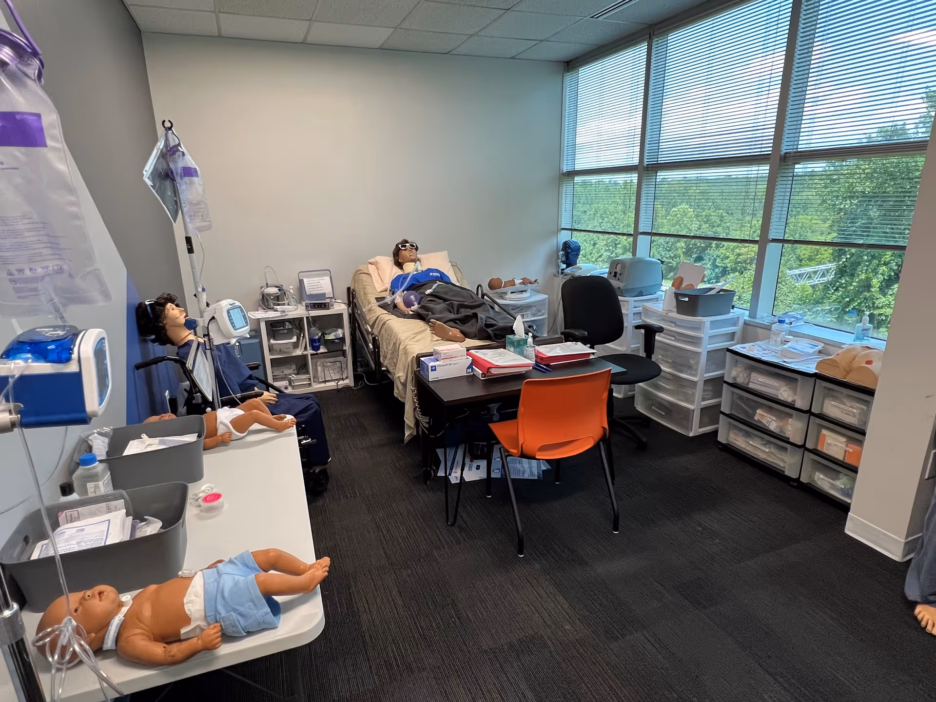 Interior medical training room with mannequins, medical equipment, desks, and large windows at Maxim Greensboro.