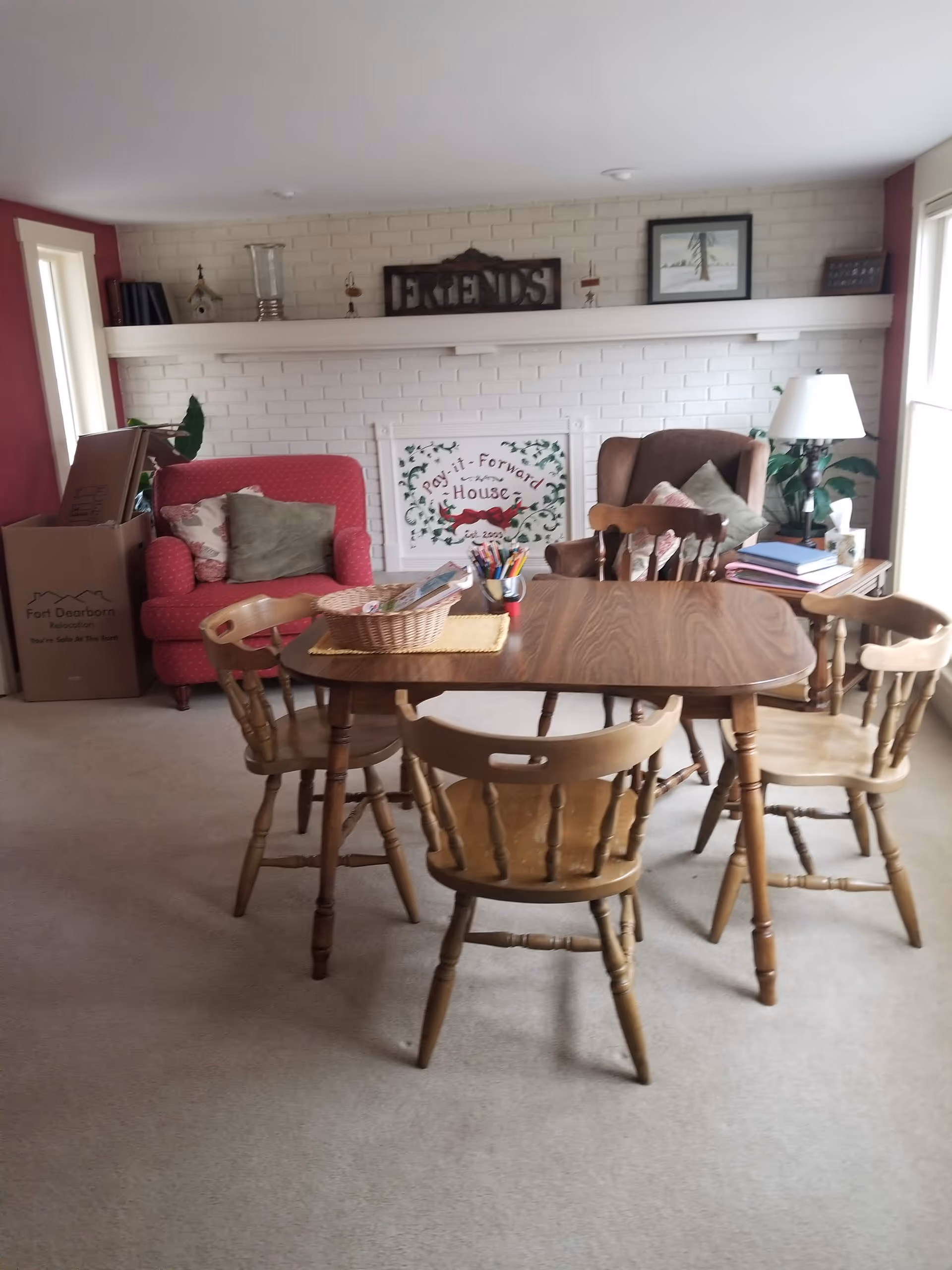 Cozy dining area featuring a wooden table, chairs, a pink sofa, and a brick fireplace.