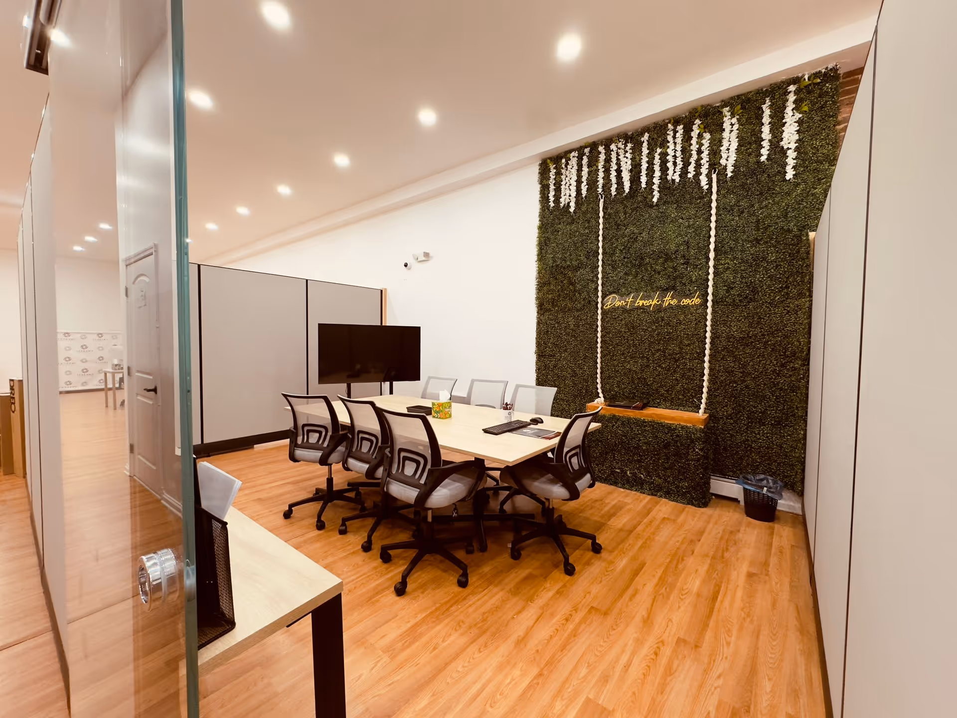 Modern conference room with a long table, chairs, and a green plant wall.