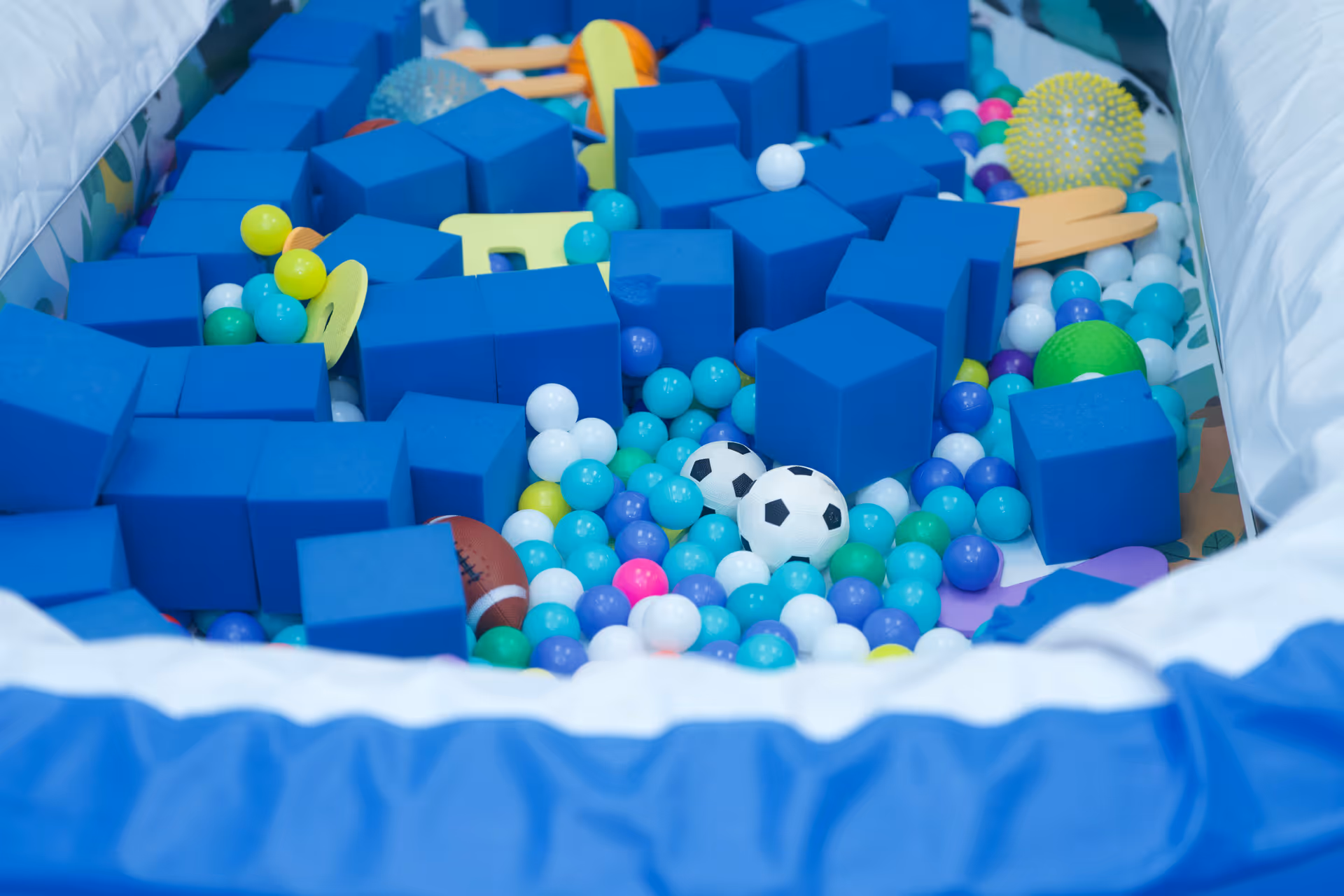 Indoor ball pit with blue foam blocks and colorful plastic balls.