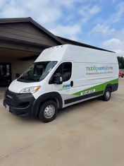 White MobilityWorks shuttle van parked in front of a senior facility building.