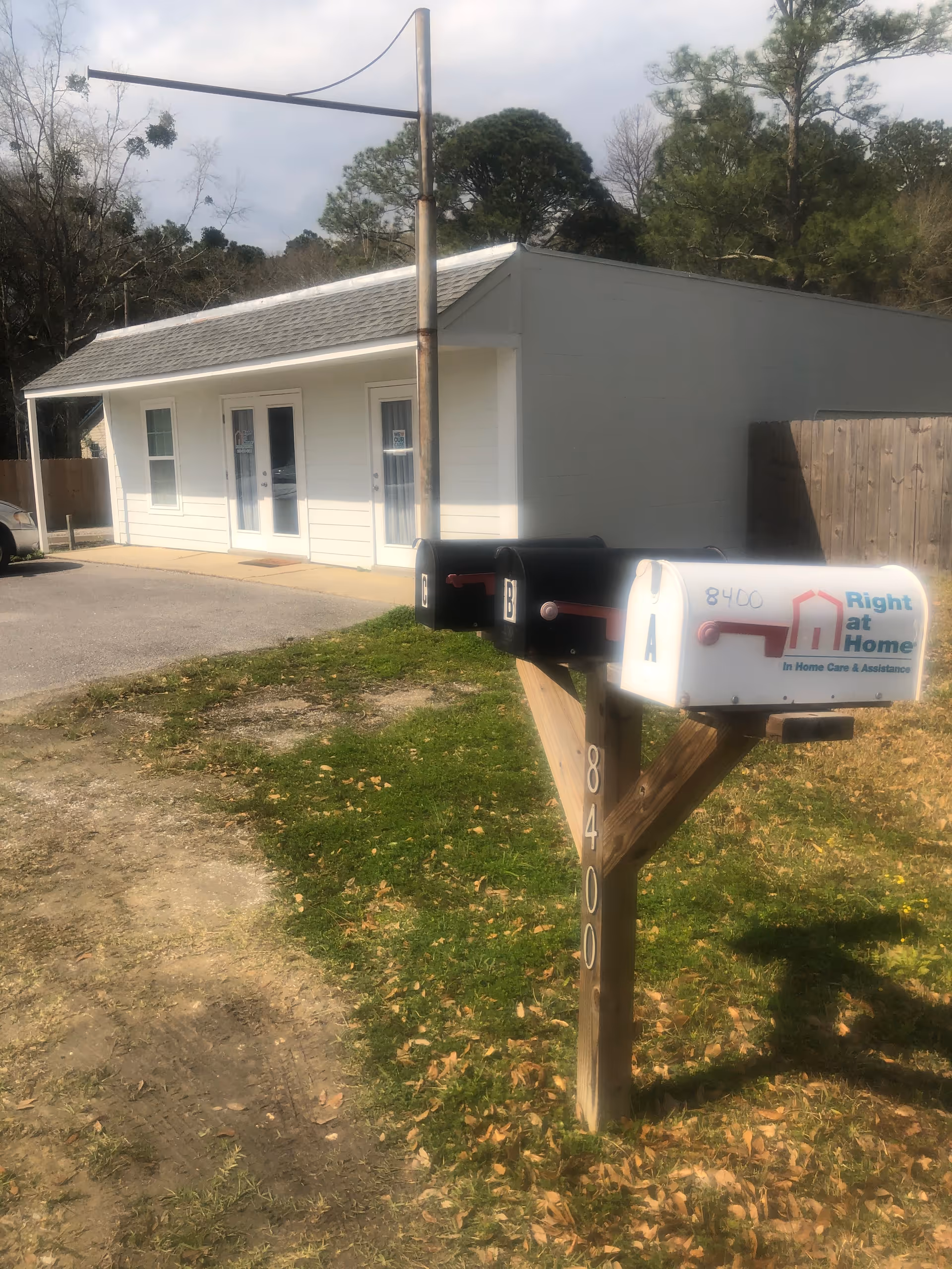 Small white building with double doors, driveway, and Right at Home mailbox in front.