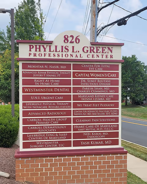 Outdoor sign for Phyllis L. Green Professional Center with tenant listings by the road
