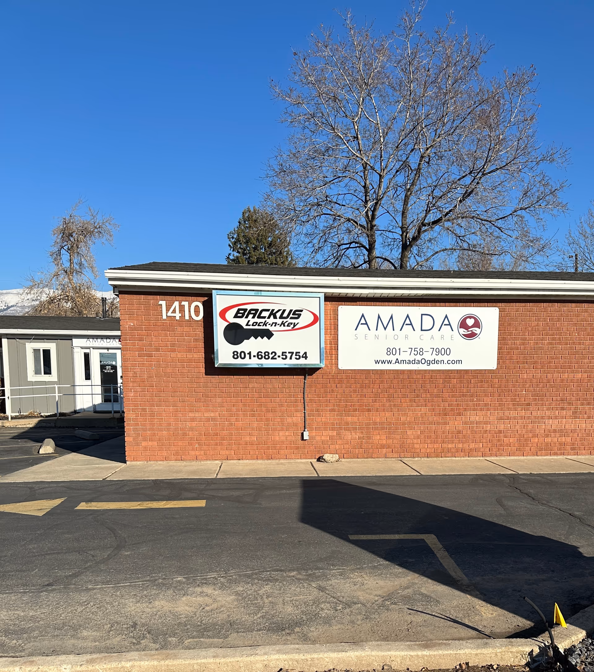Brick building with Amada Senior Care and Backus signs along a parking lot outside.