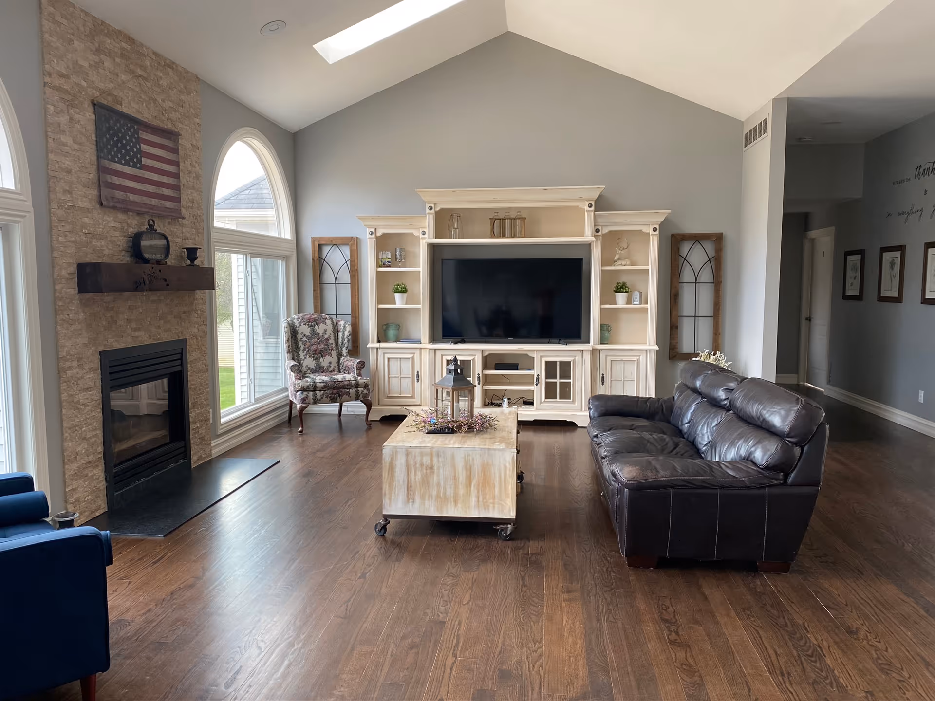Sunny living room with a cream entertainment center, fireplace, and leather sofa.