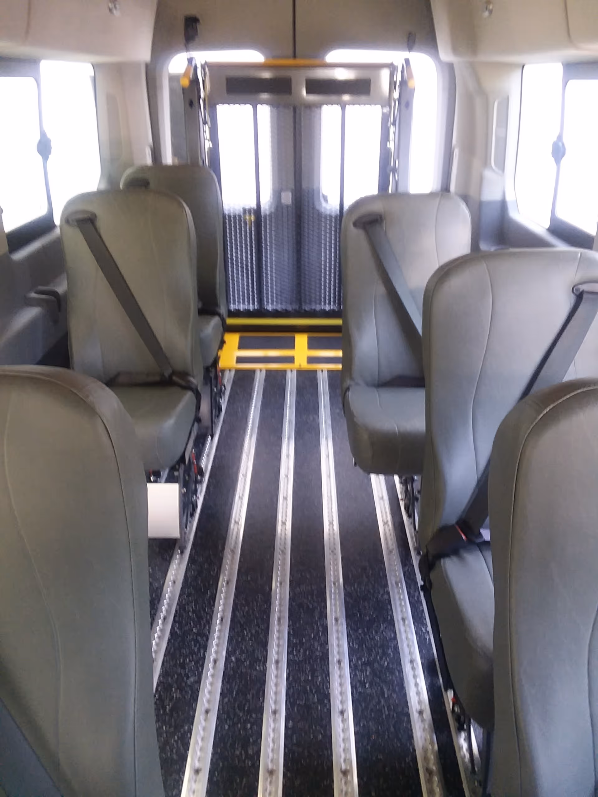 Interior of a mobility van with rows of seats and a rear entry.