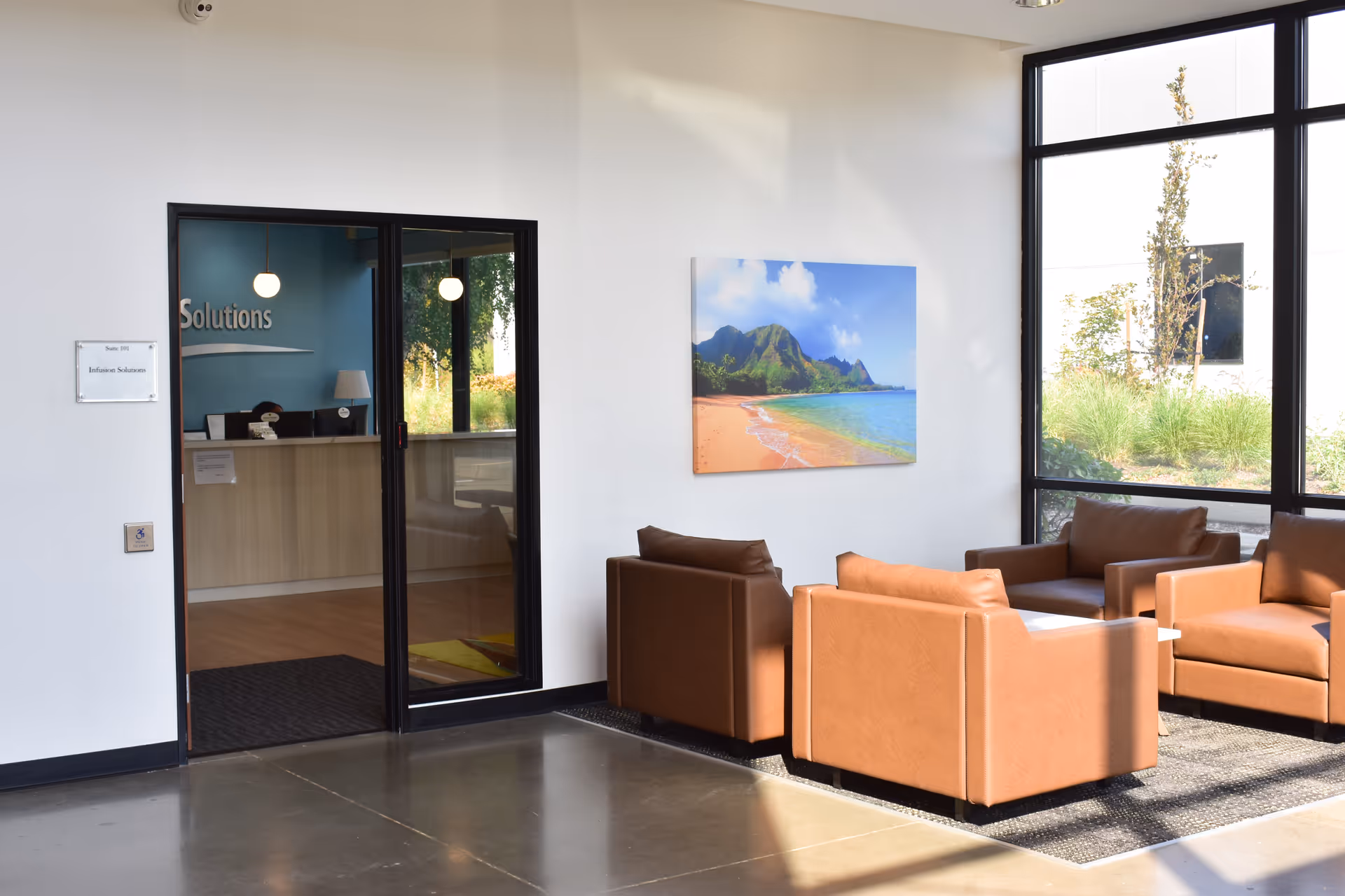 Bright lobby area with brown couches, large windows, and a reception doorway.