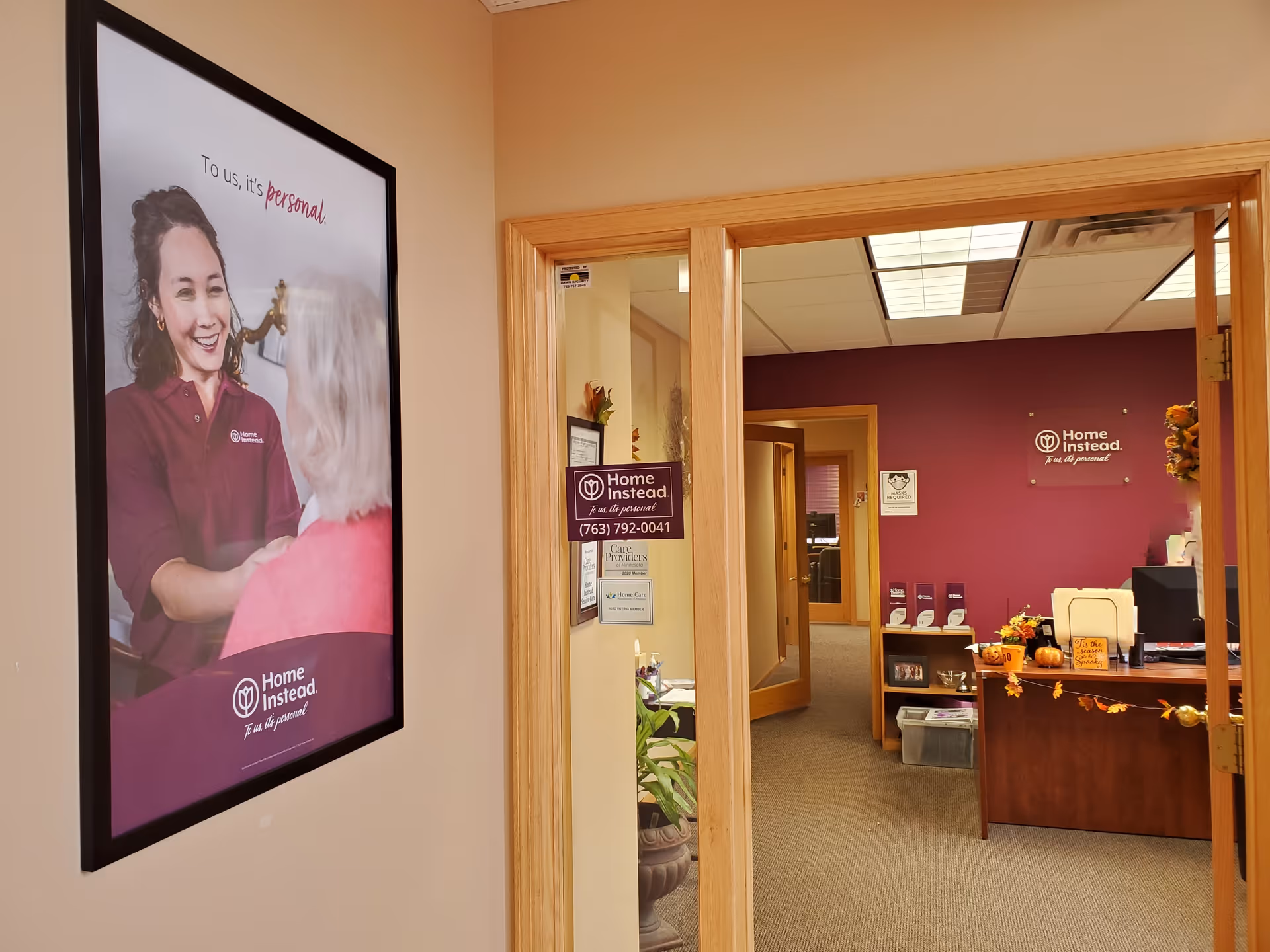 Interior office hallway with a large poster on the left and a reception area ahead.