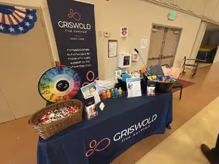 Promotional table with Griswold branding, prize wheel, and gift baskets in a care facility hallway.