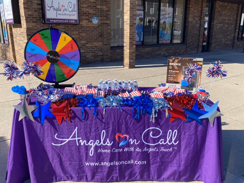 Outdoor promotional table for Angels On Call Home Care with colorful wheel and decorations.