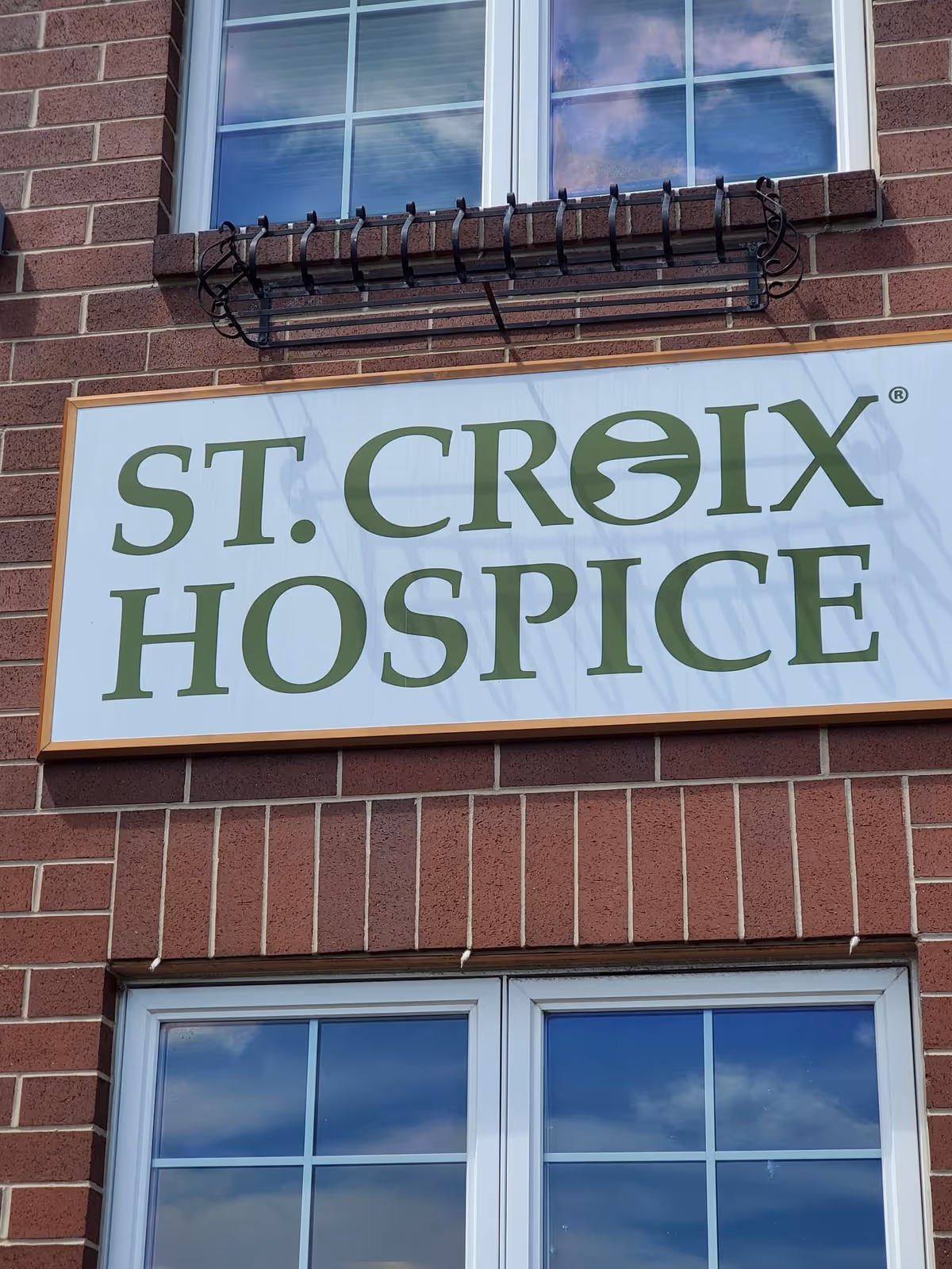 Brick building exterior with a large sign reading St. Croix Hospice and windows above.