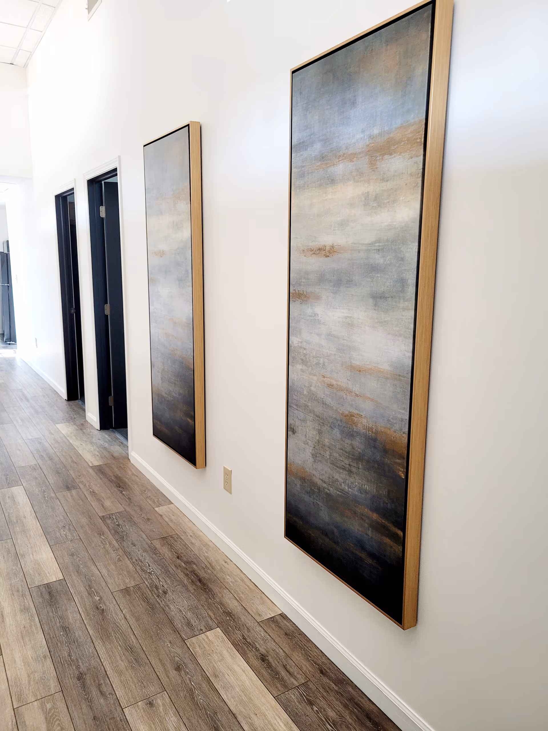 Bright senior facility hallway with two tall abstract paintings on white walls.