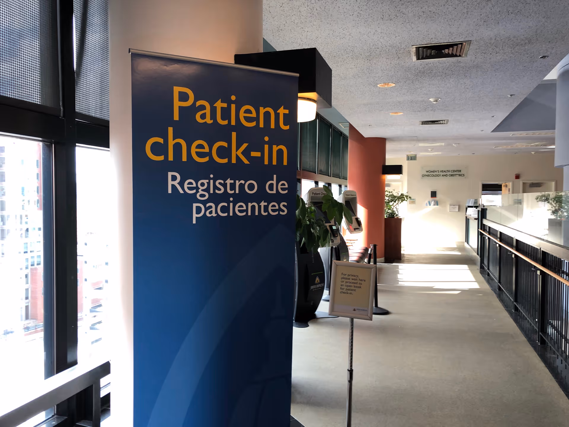 Hospital corridor featuring patient check-in sign and reception desk.
