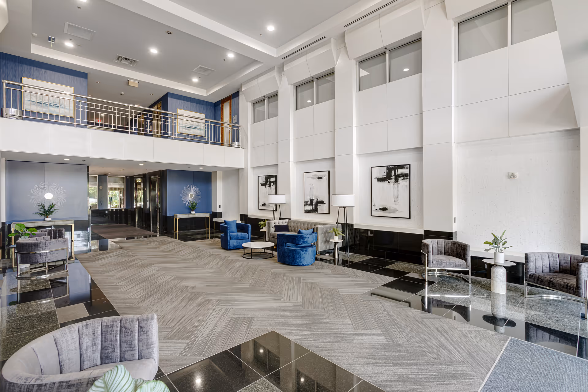 Open contemporary hotel-style lobby with blue seating, tall windows, and marble accents.
