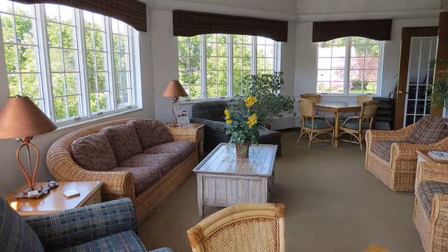 Cozy lounge area with wicker seating, coffee table, and large windows.