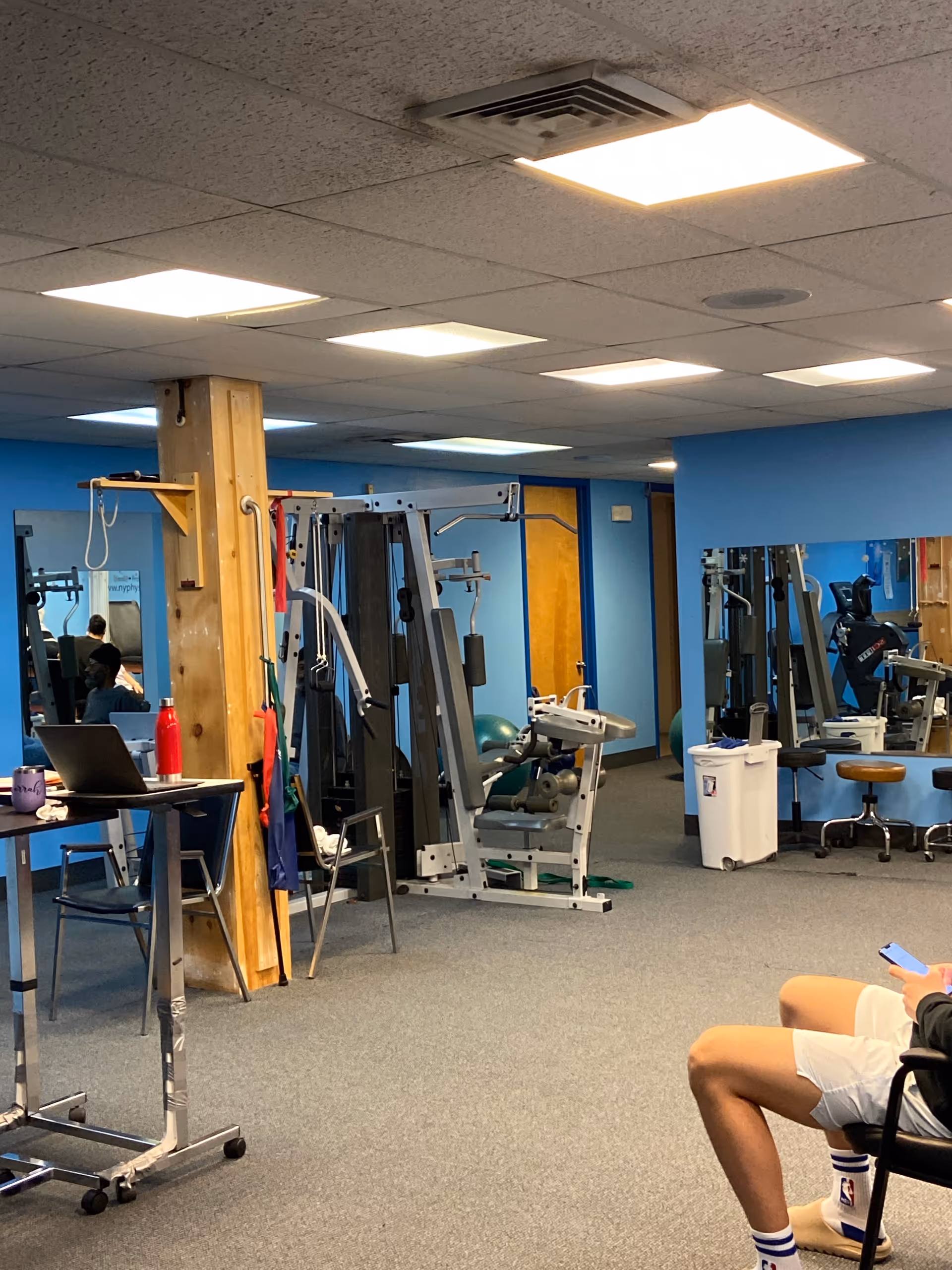 Indoor physical therapy gym with workout machines and blue walls in a senior facility.