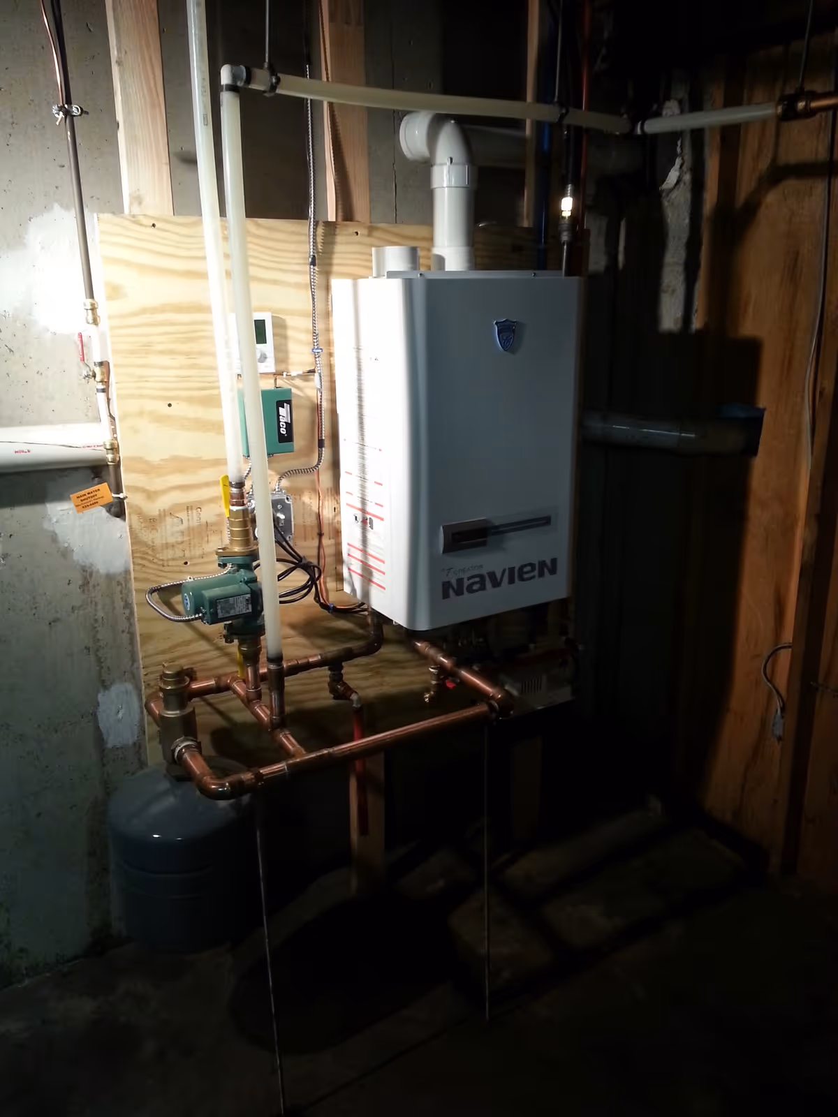 Basement utility room features a Navien boiler, exposed copper pipes, and mechanical equipment.