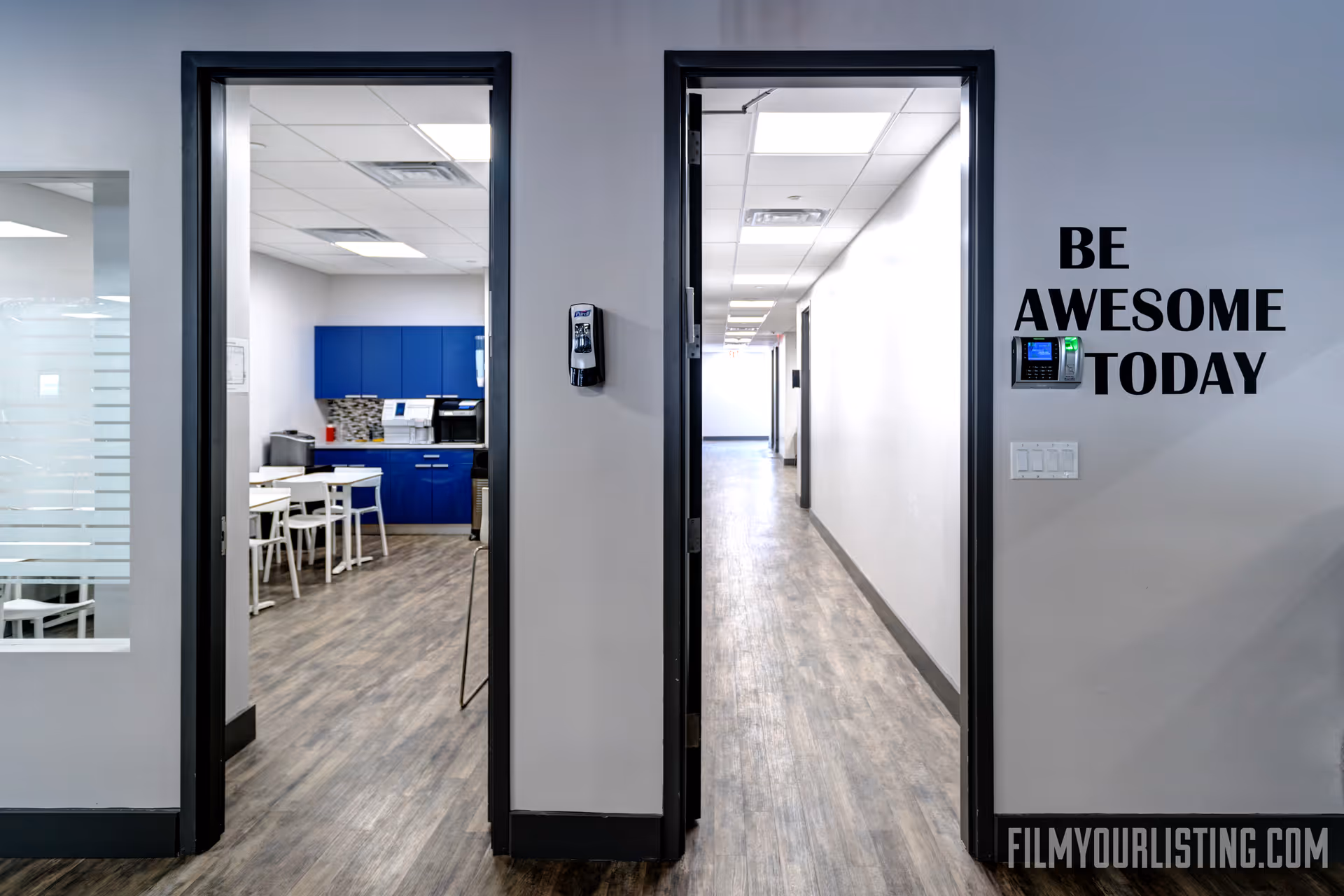 Hallway view of a modern facility with kitchenette left and Be Awesome Today wall text.