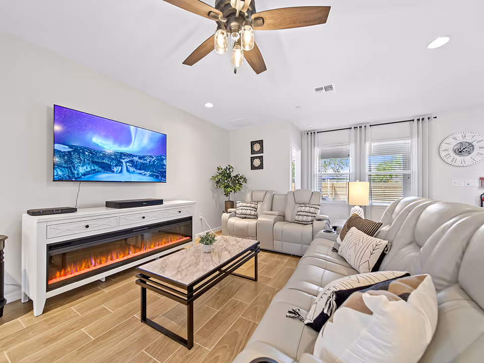 Modern living room in a senior facility with beige seating, fireplace, and TV.