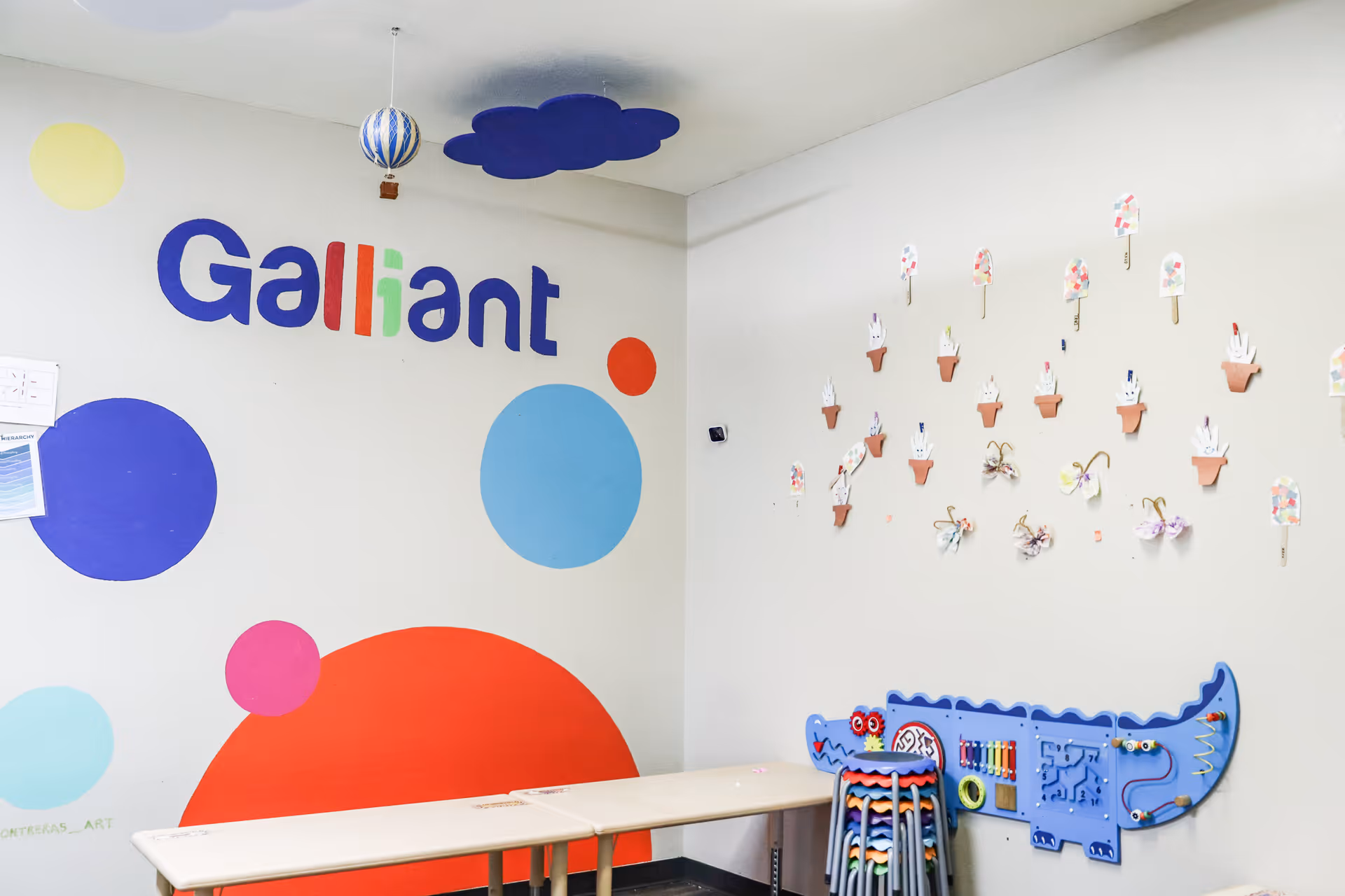Bright indoor wall with Galliant branding, colorful shapes, and children's activity area.