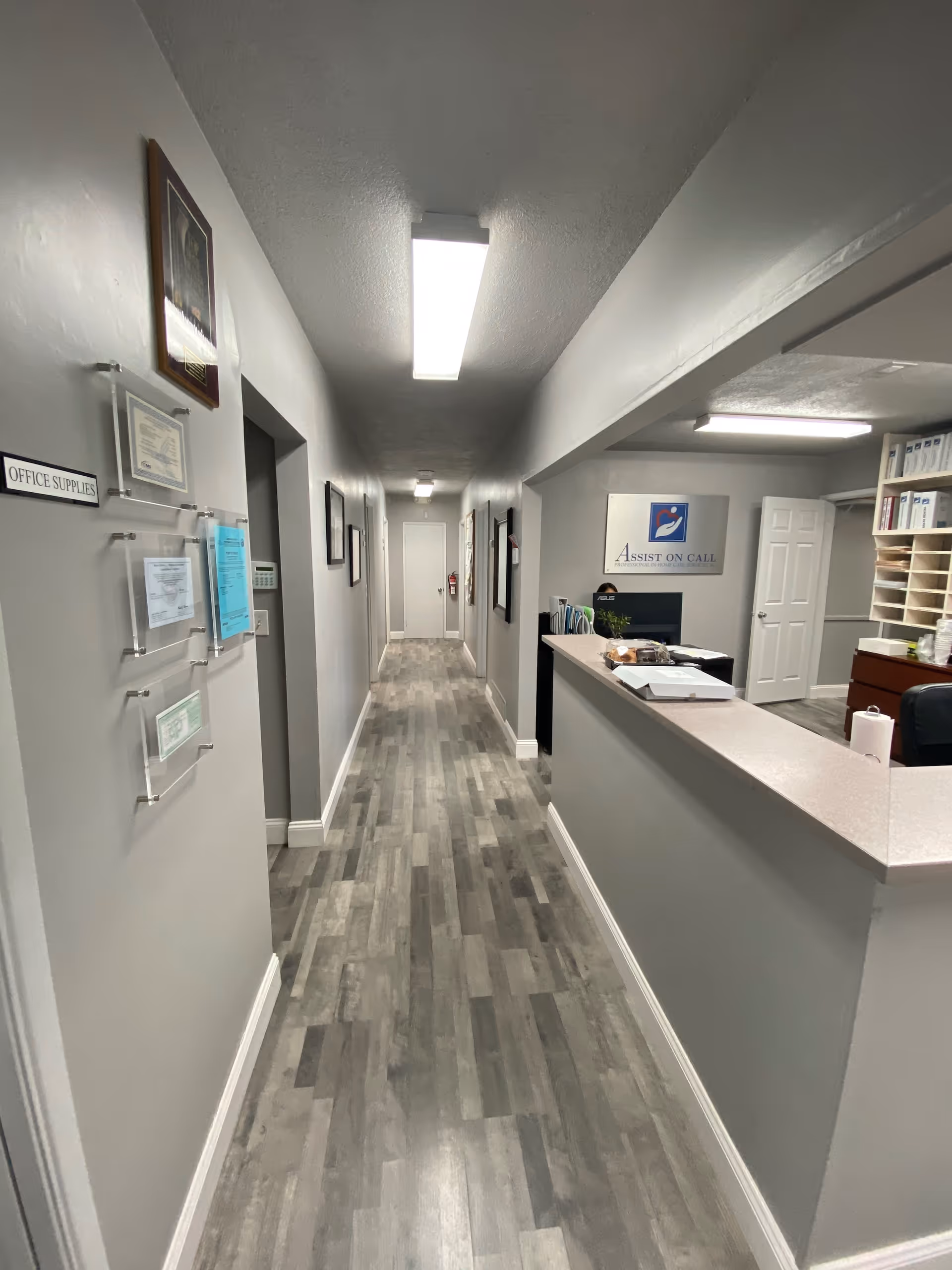 Long indoor hallway at Assist On Call with a reception desk on the right.