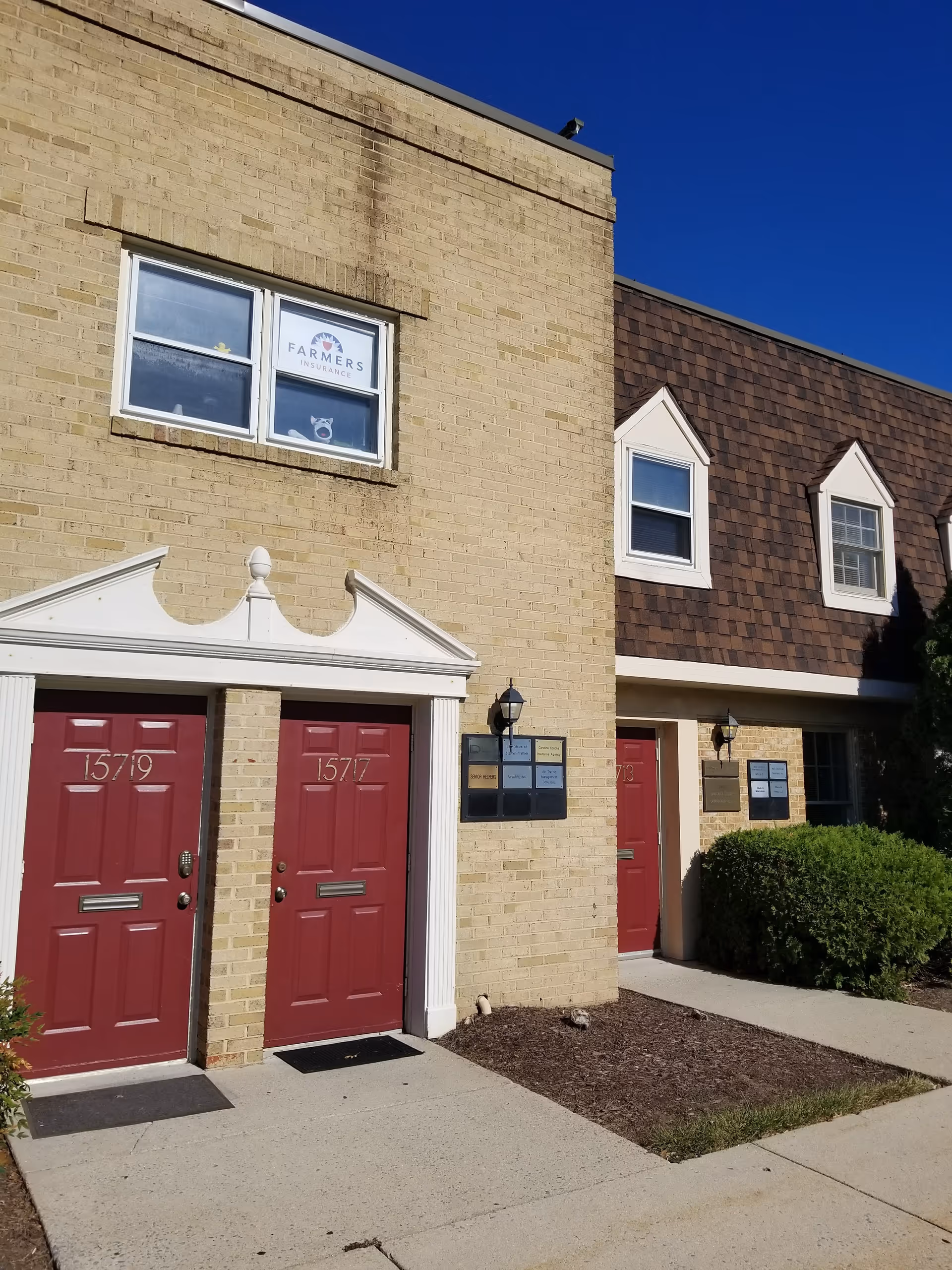 Exterior view of a brick building with red doors and upper windows.