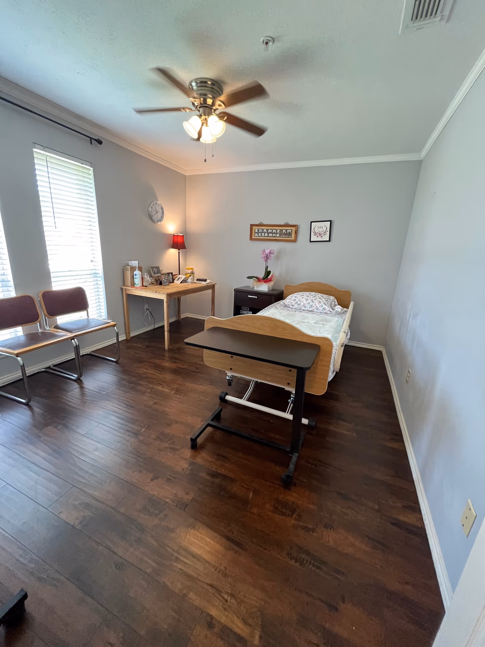 A patient bedroom in a senior care facility with bed, desk, and chairs.