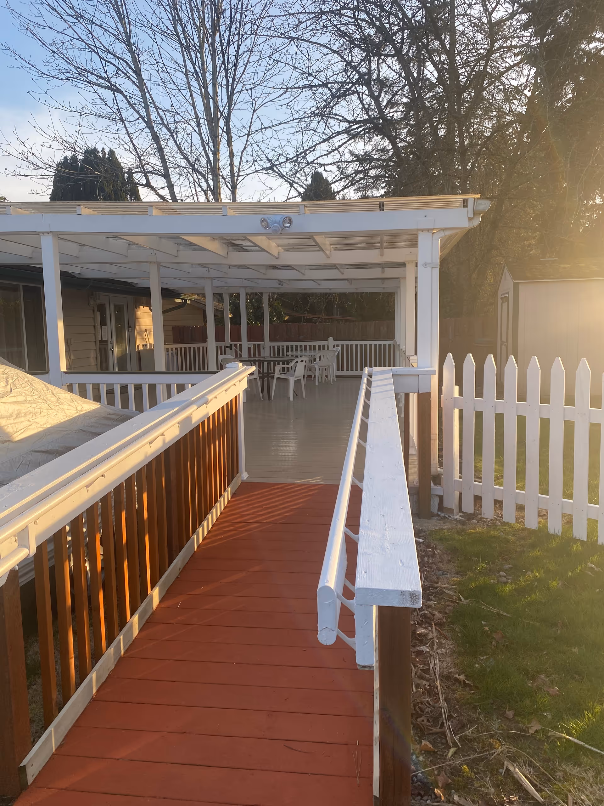 White wooden ramp leads to a covered outdoor patio with tables and chairs.
