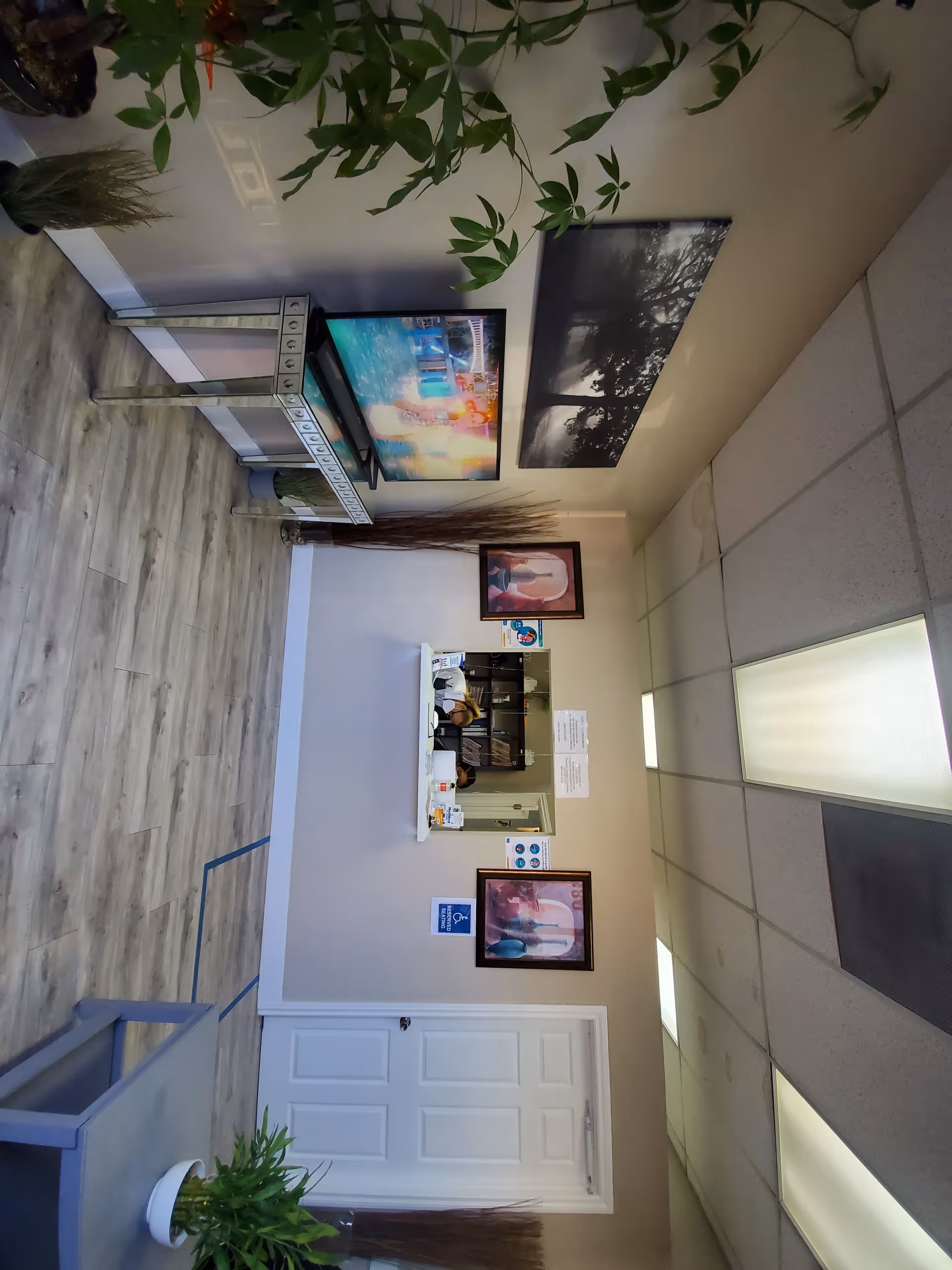 Interior reception lobby of Clinica Monsenor Oscar A. Romero with plants, framed art, and desk.