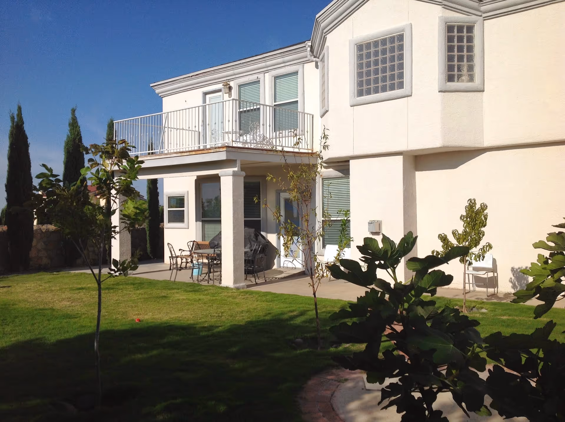 Two-story beige senior living home with a covered patio and outdoor seating.
