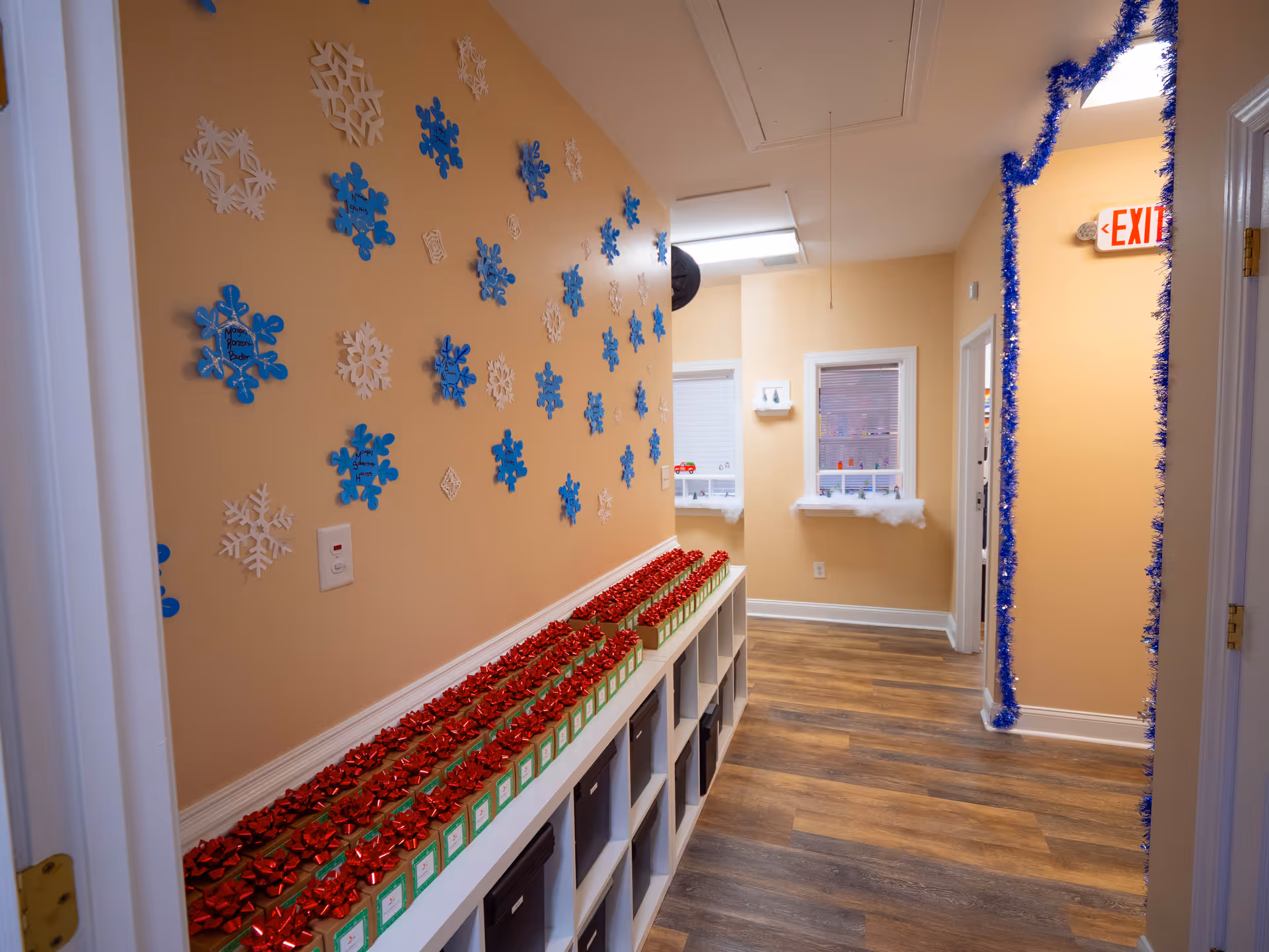 Indoor hallway with beige walls, winter snowflake decor, and red gift boxes along cubbies.