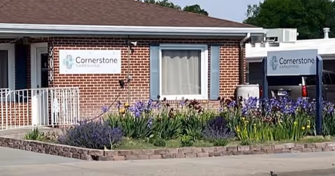 Brick Cornerstone Caregiving building exterior with a flower bed and signs.