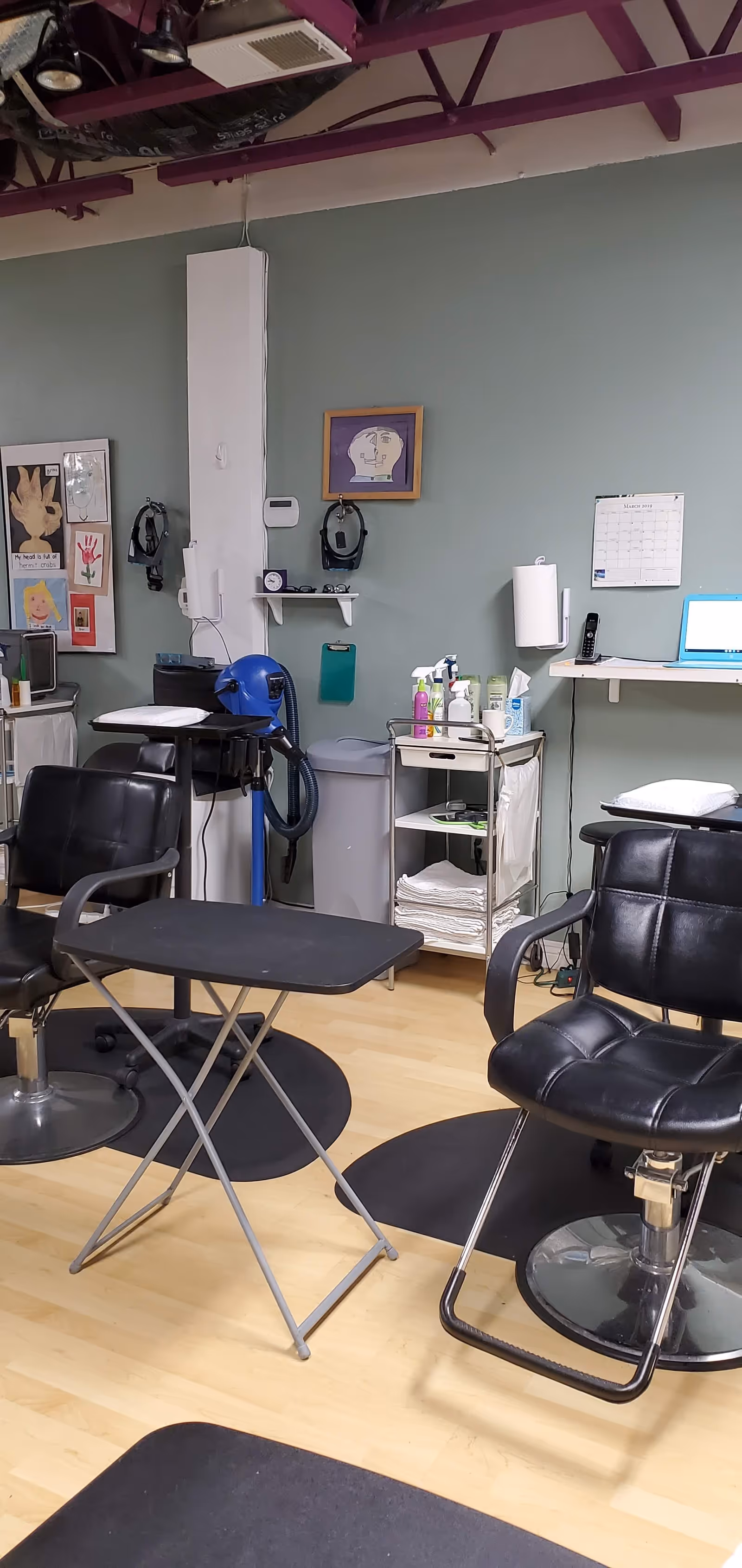 Interior treatment room with black salon chairs, a foldable table, and medical supply cart.