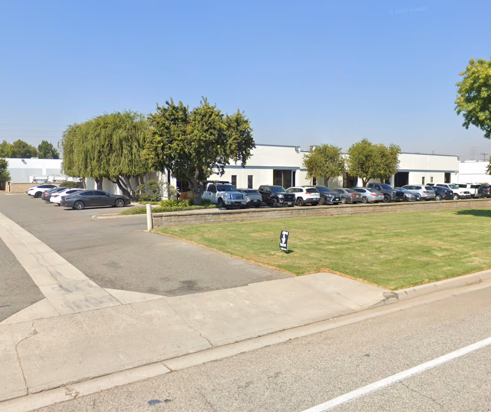 Exterior view of a single-story facility with a parking lot and trees.
