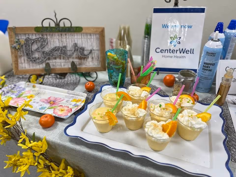 Tray of small dessert cups with whipped topping on a table, CenterWell Home Health sign behind.