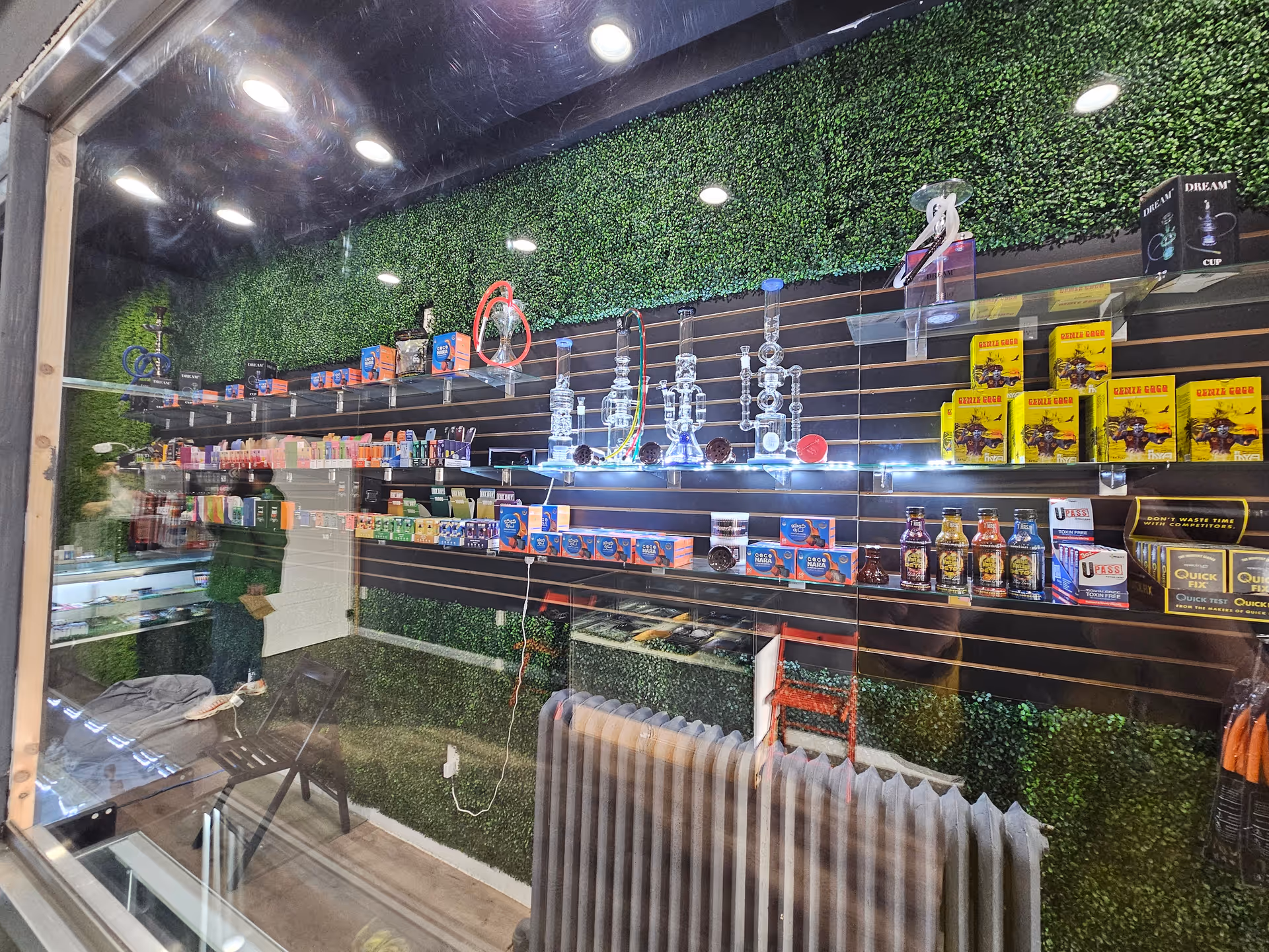 Interior of a smoke shop with glass display shelves and a green wall.