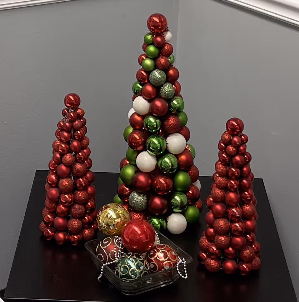 Three ornament trees made of red, green, and white balls on a black table.