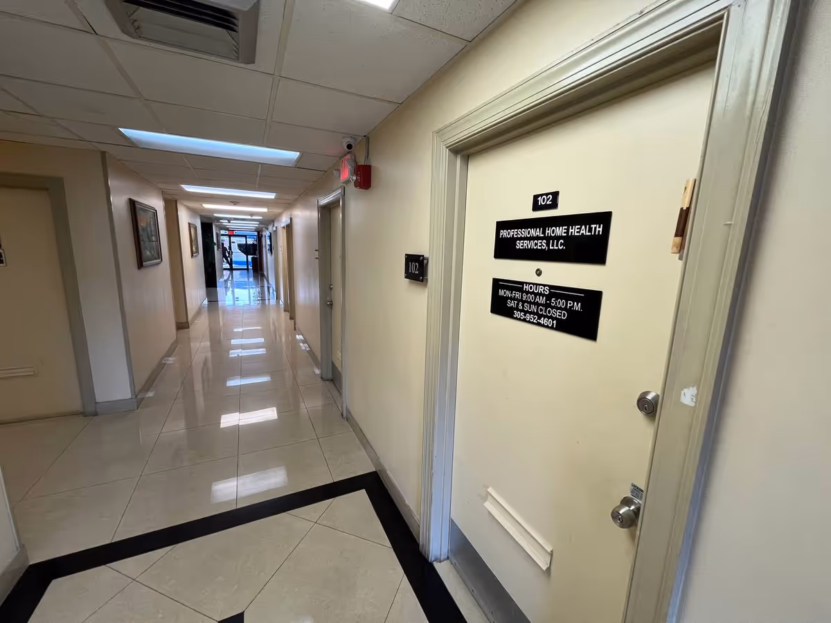 Long, well-lit hallway of a senior facility with closed doors and a black office sign.