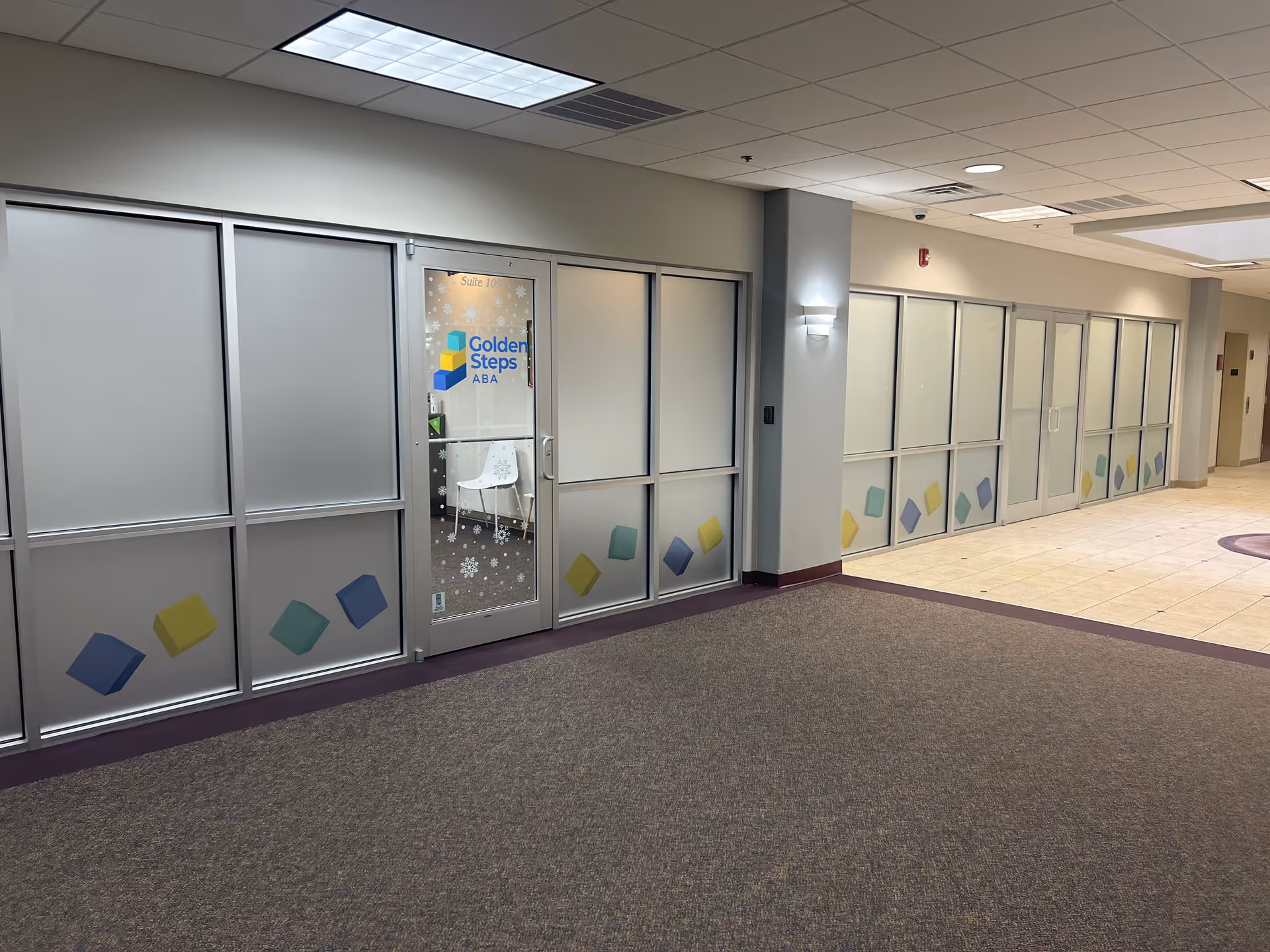 Interior hallway with frosted glass doors displaying Golden Steps ABA signage.