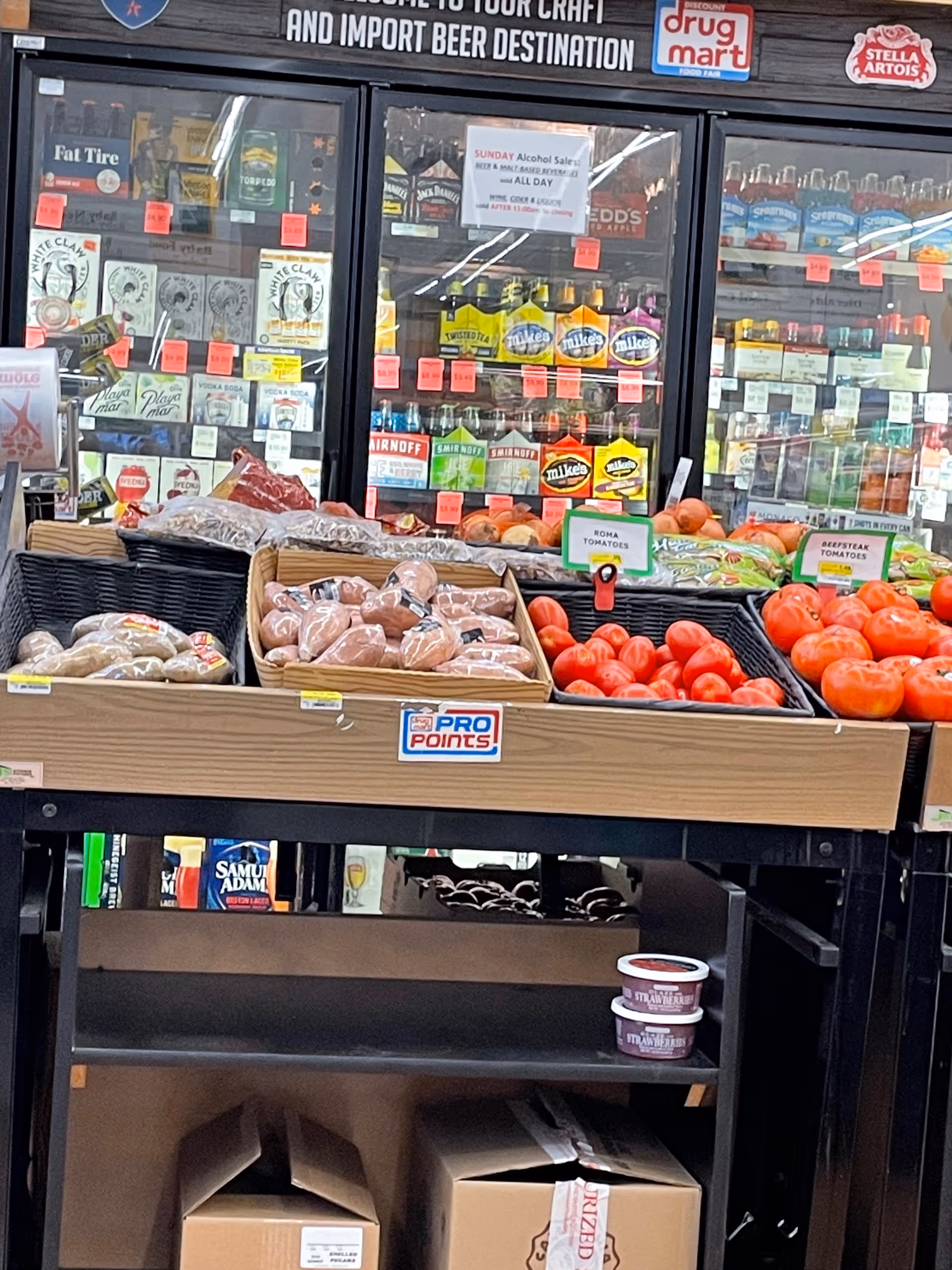 Produce display featuring onions and tomatoes inside a Discount Drug Mart store.